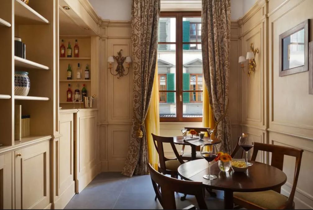 Two round dining tables in a cozy room with large windows and patterned drapes