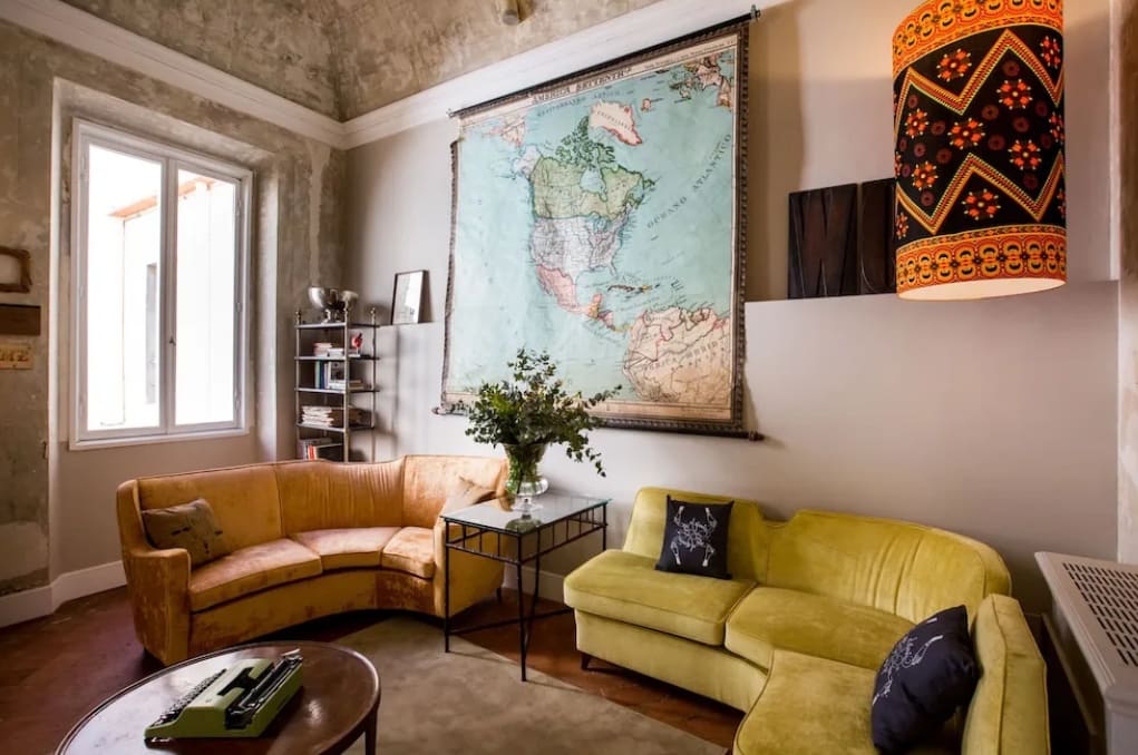An vintage hotel lounge area with colorful sofas and a large map on the wall