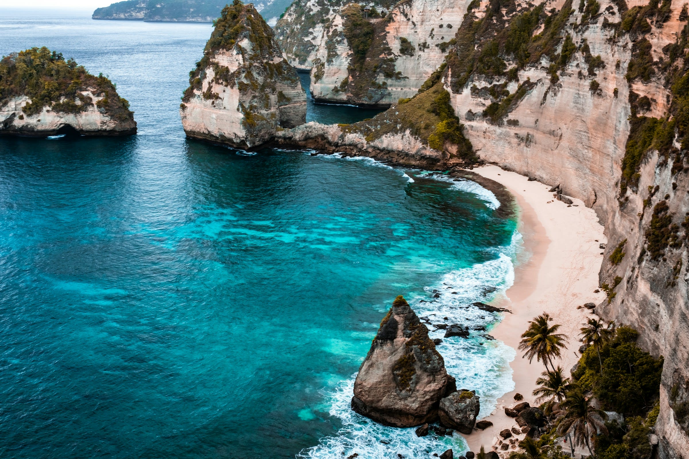 Turquoise ocean water below tan and black cliffs