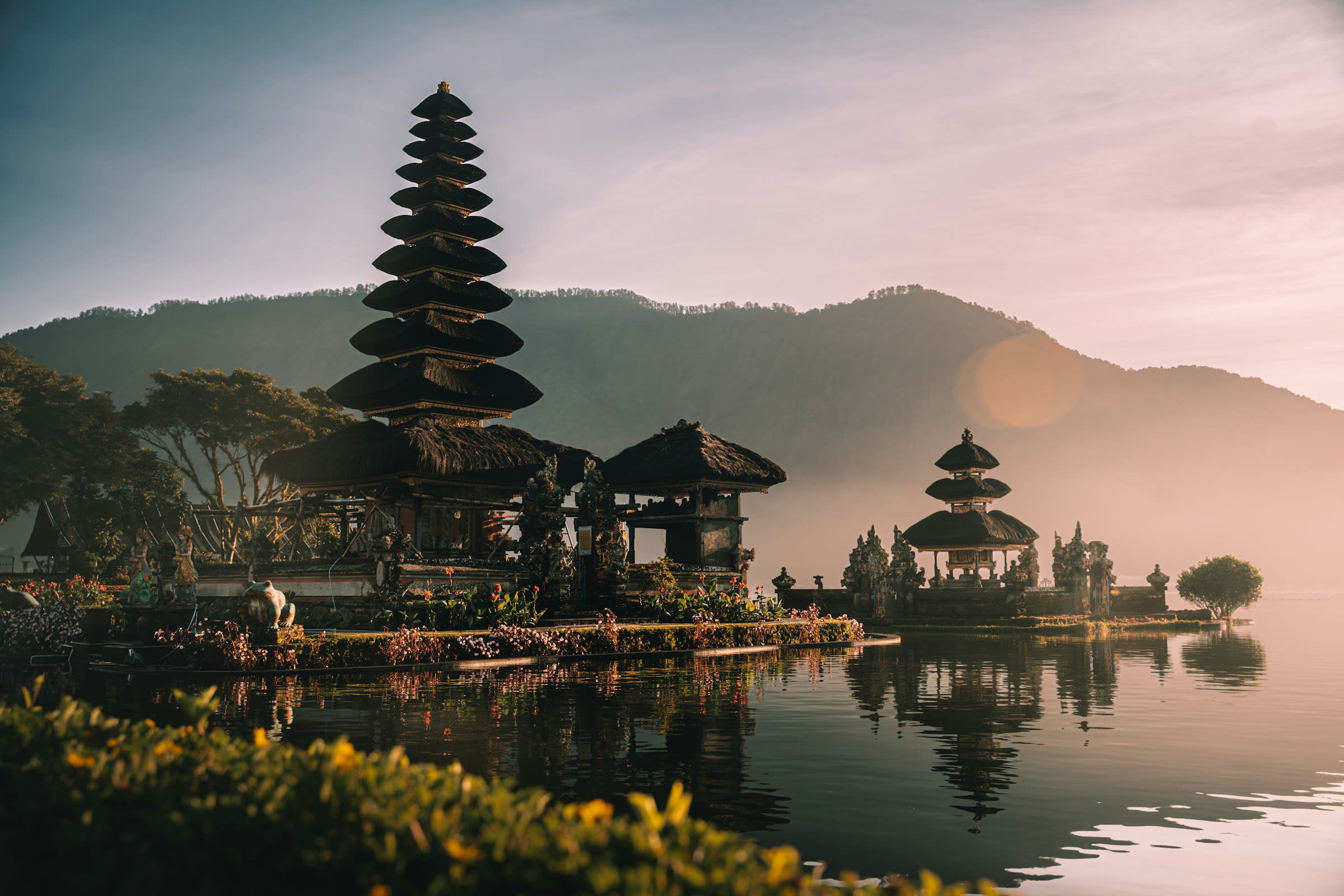 Ornate temple on a lake and mountains in the background at sunrise