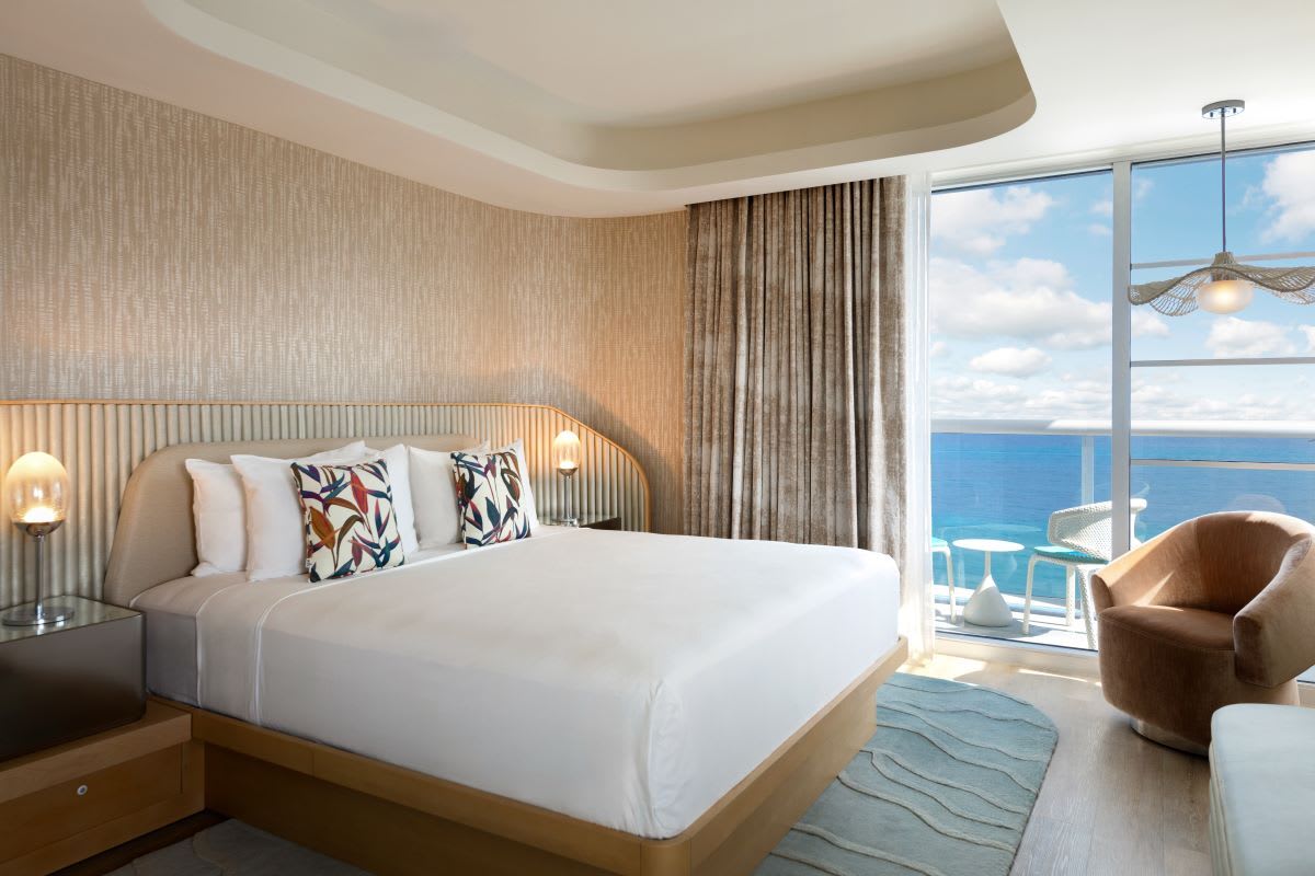 A hotel bedroom with ocean views and modern, neutral decor