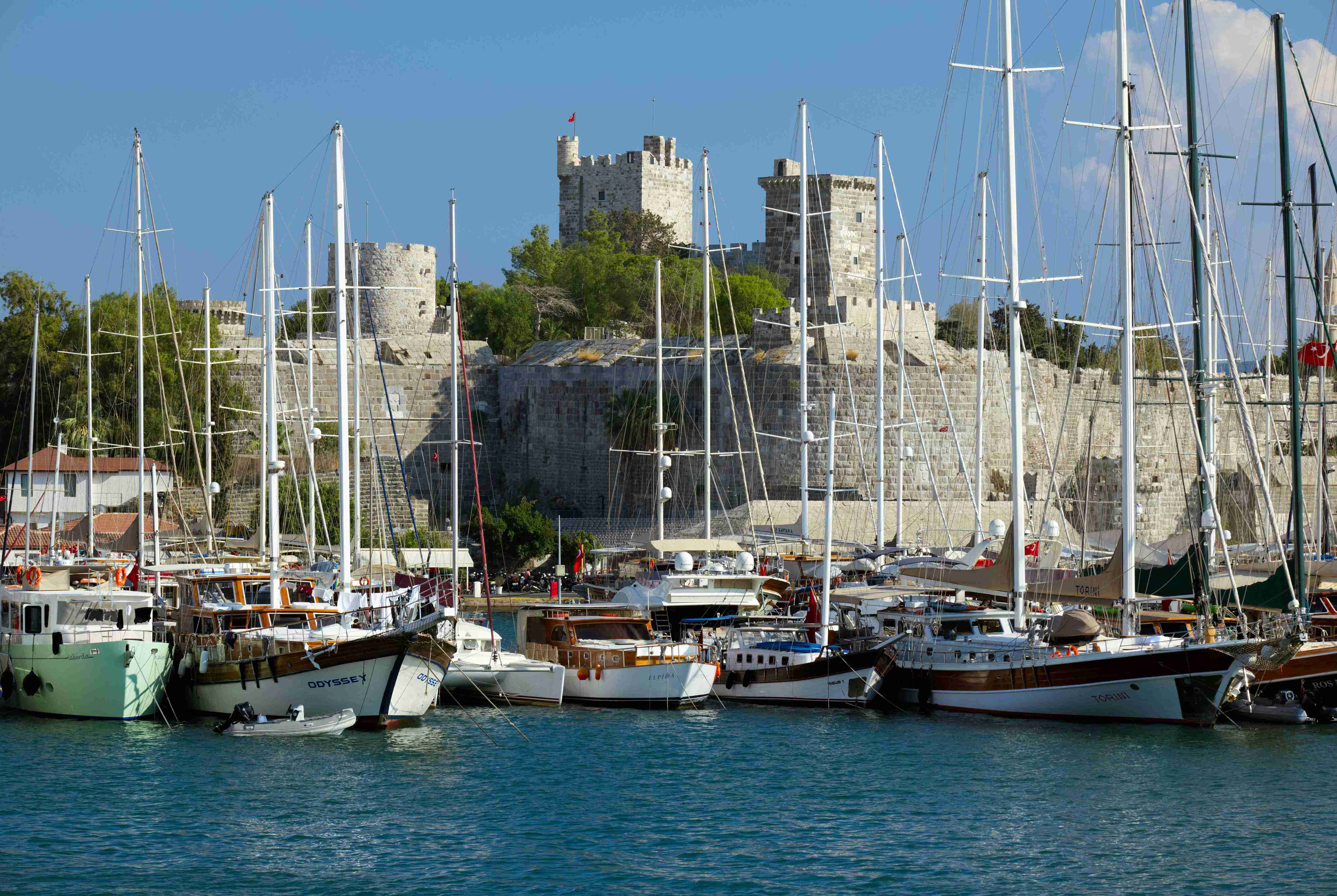 A view of boats docked at an old fort with an ancient wall and turrets