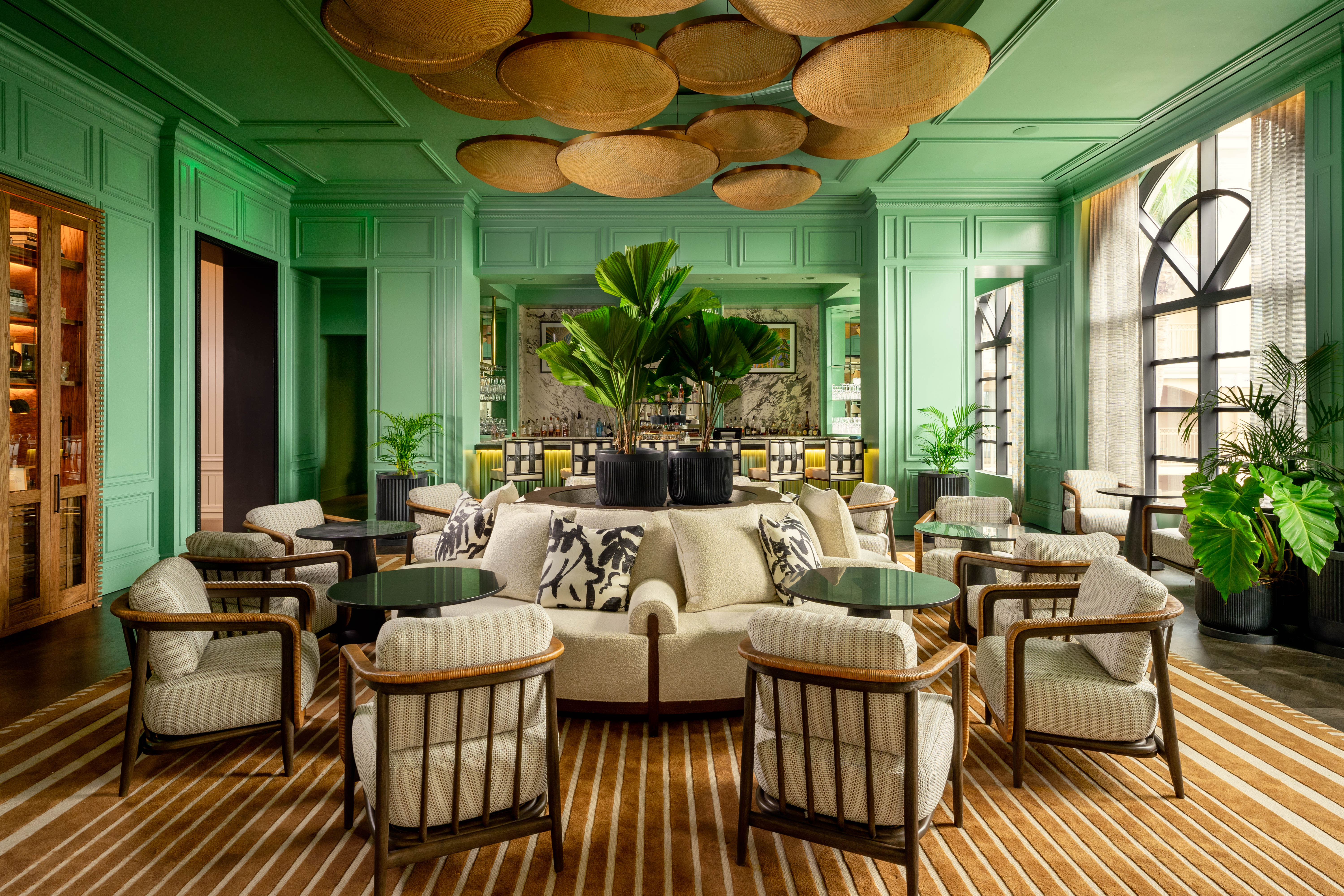 A hotel lounge area with tropical decor, light green walls and ceiling and cream seating