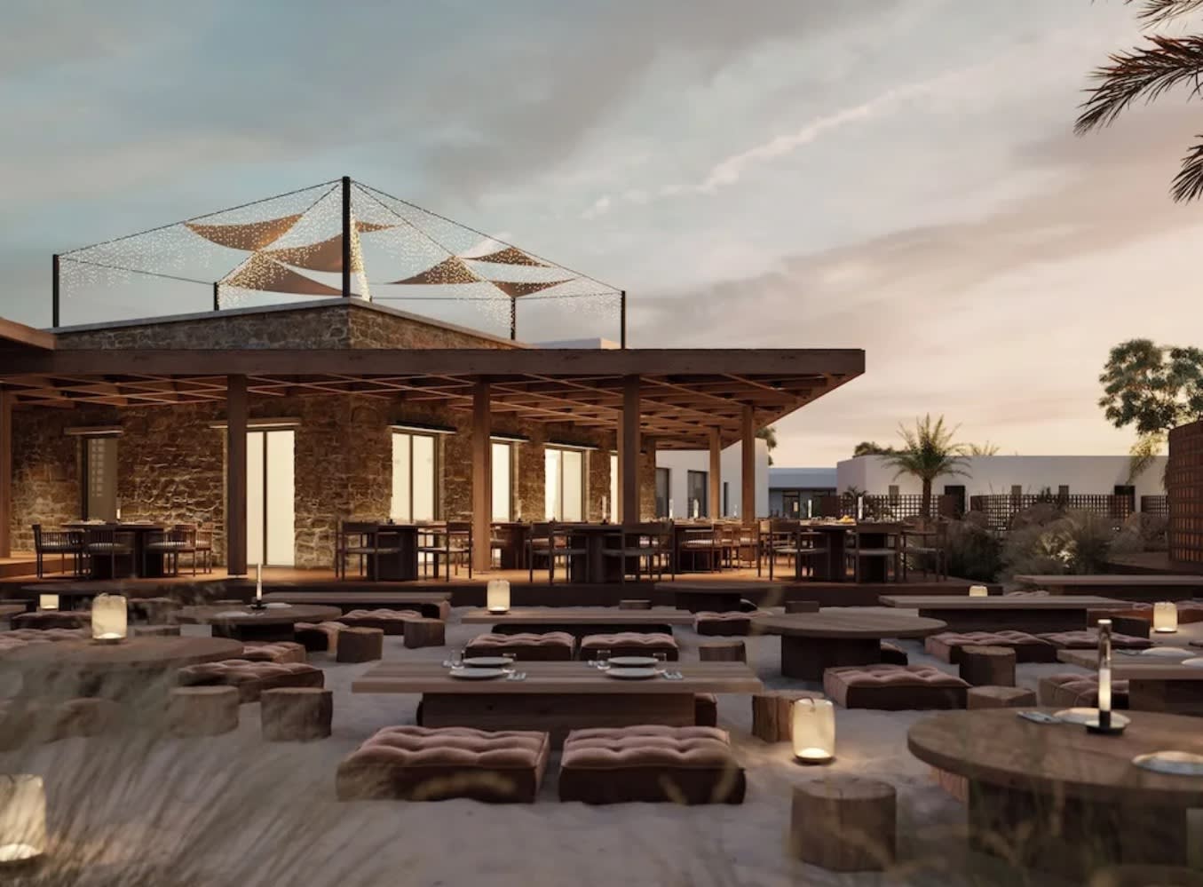 outdoor tables and seating on a beach at sunset