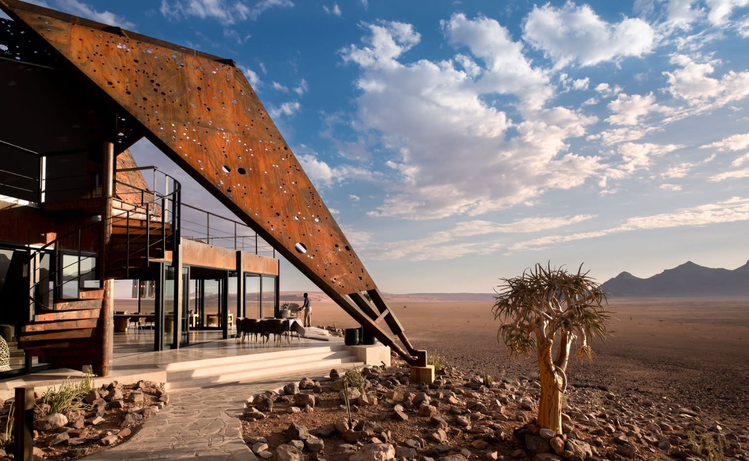 building in a desert with blue sky and puffy clouds