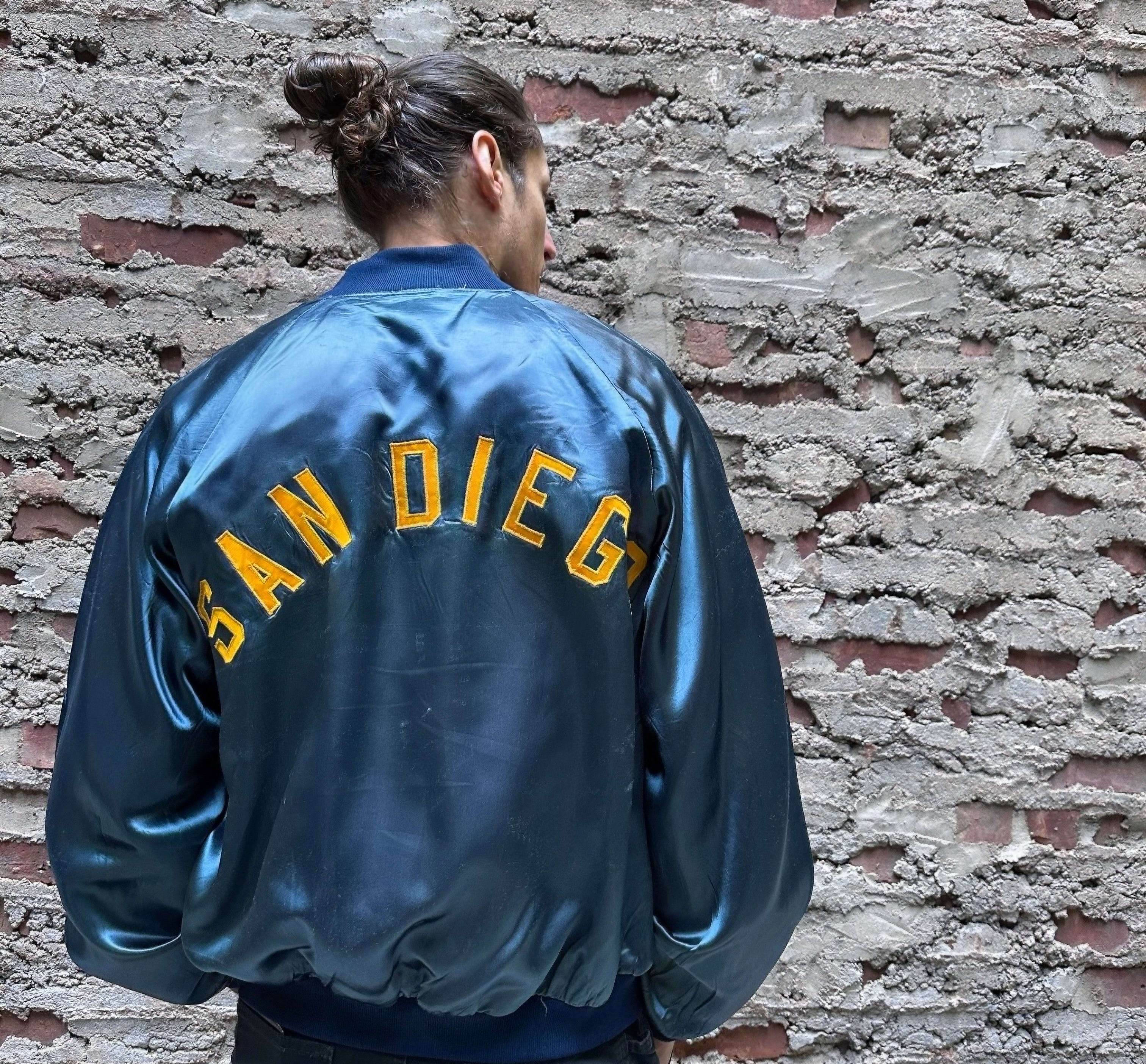a man in a silk vintage jacket that says "San Diego" on he back