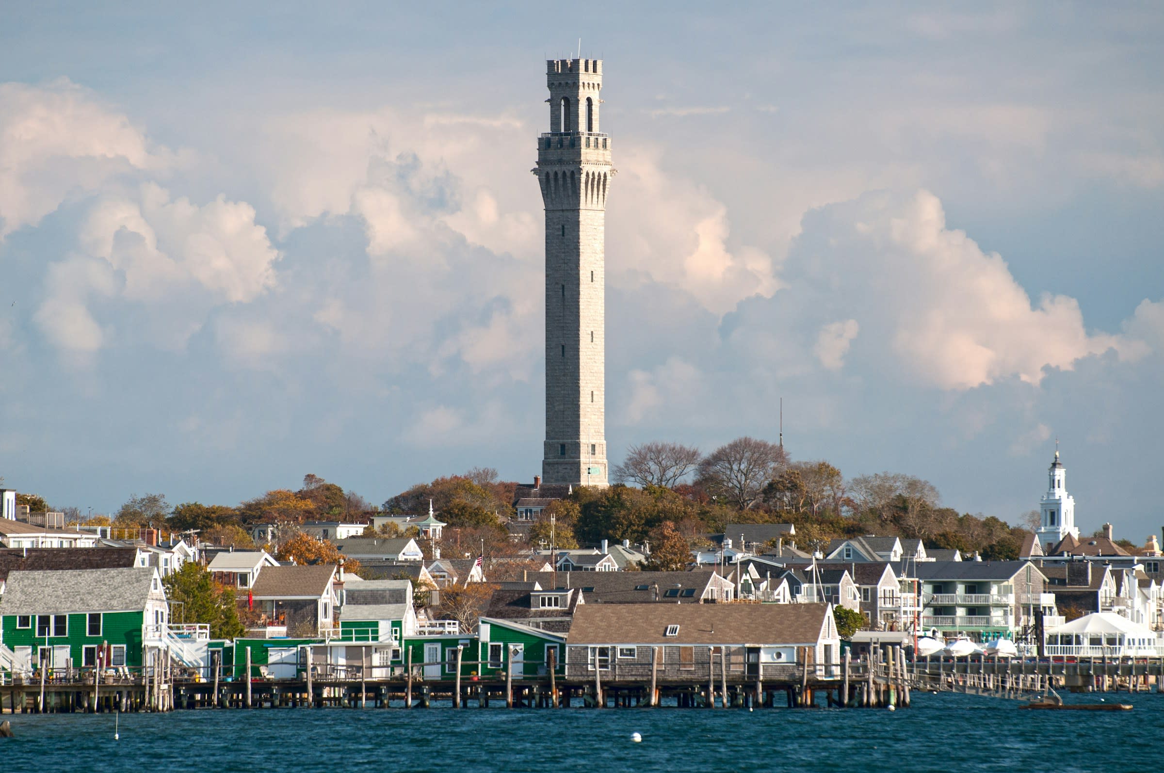 a tall grey tower over a coastal harbor city