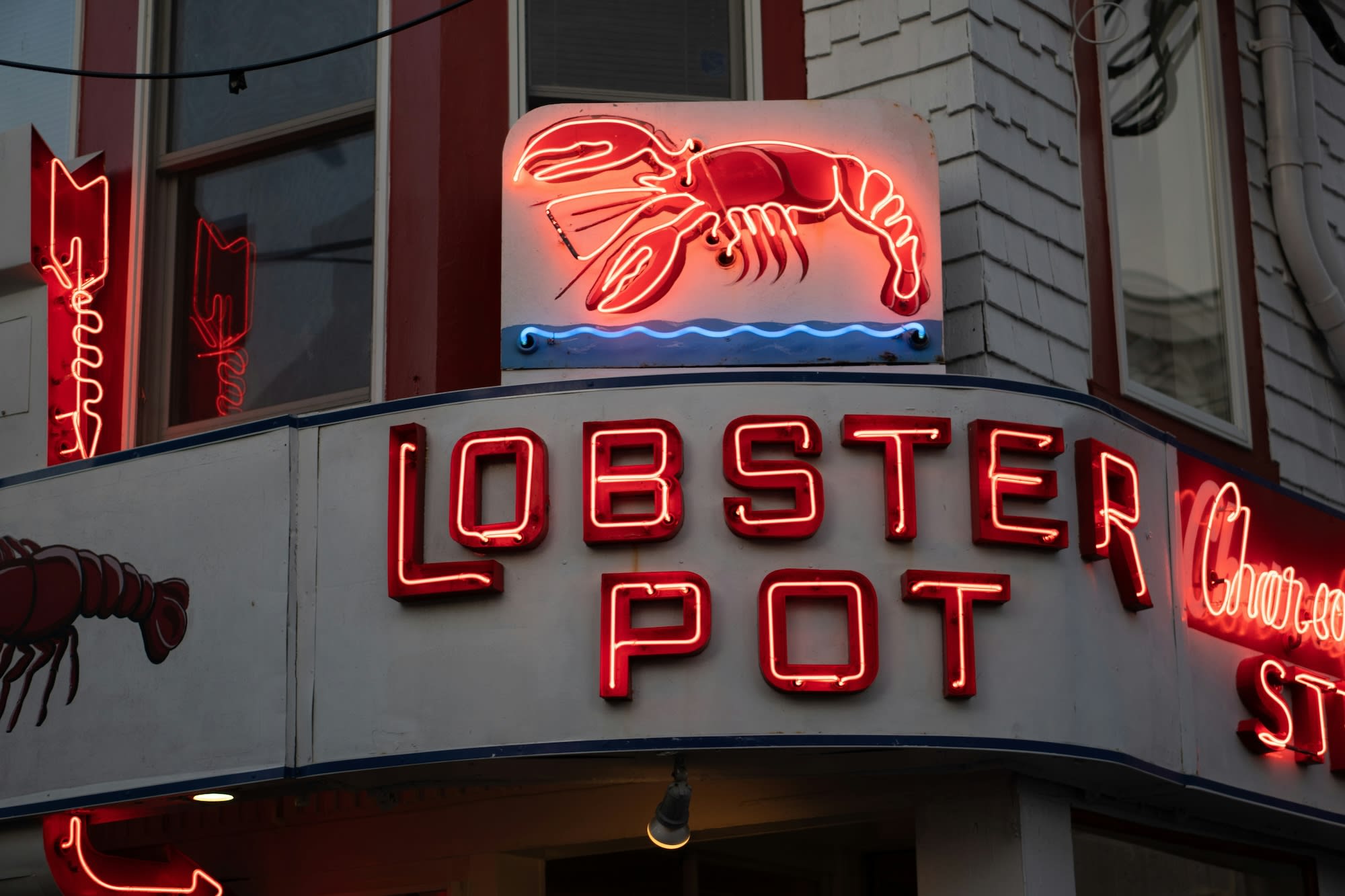 an outdoor restaurant with red letters that read "lobster pot"