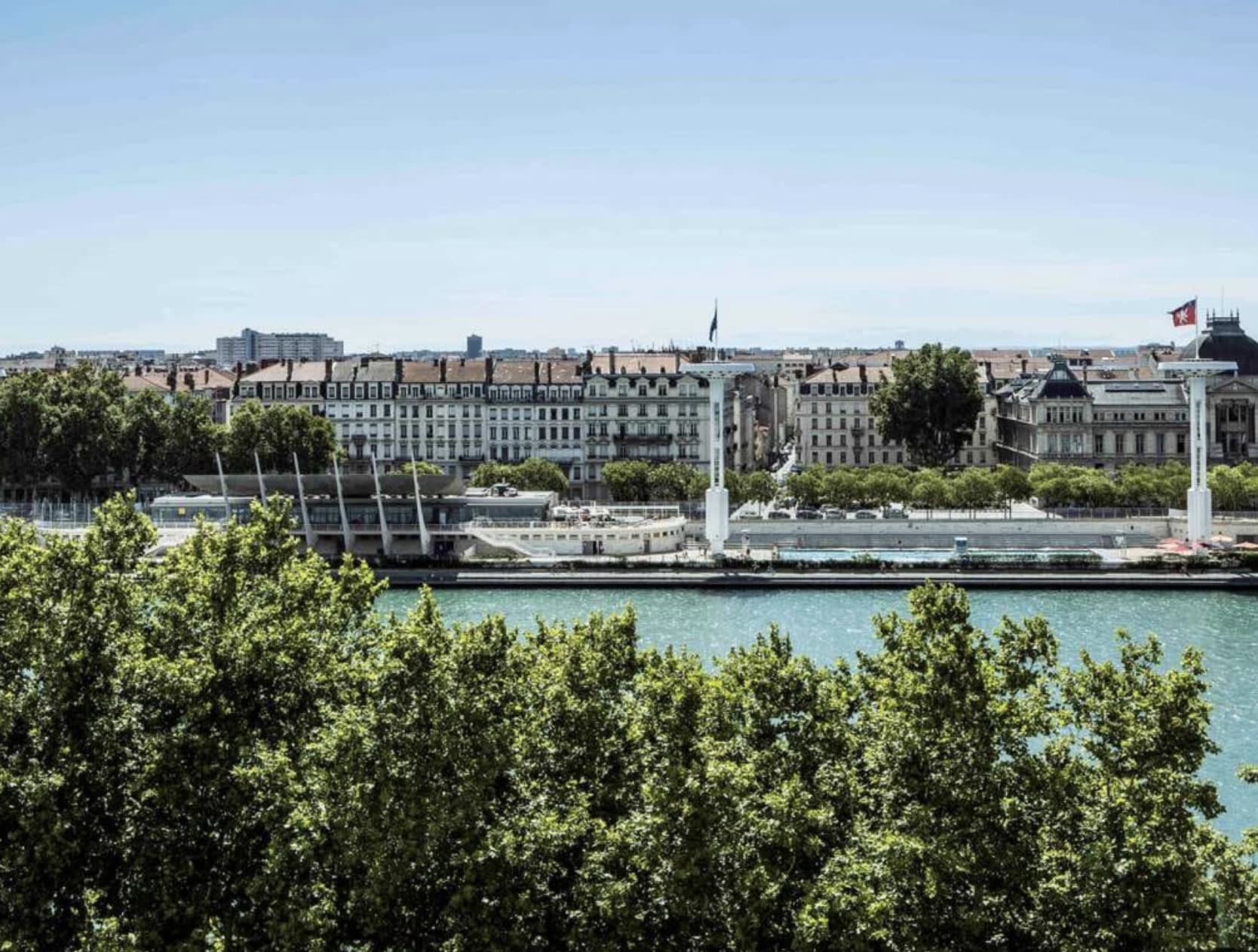 view of a river with city buildings and blue sky beyond