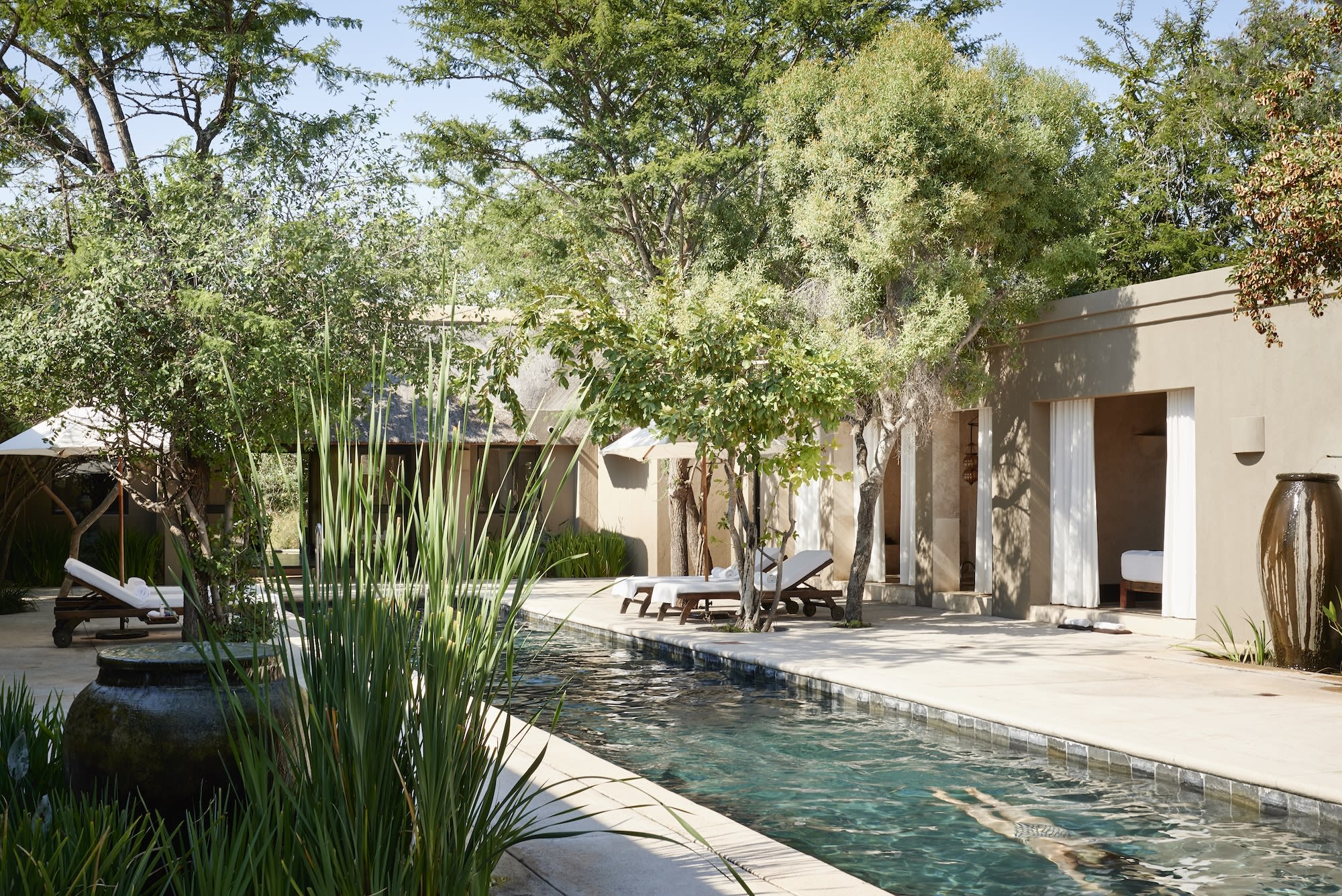 a pool in a hidden courtyard lined with luxe cabanas