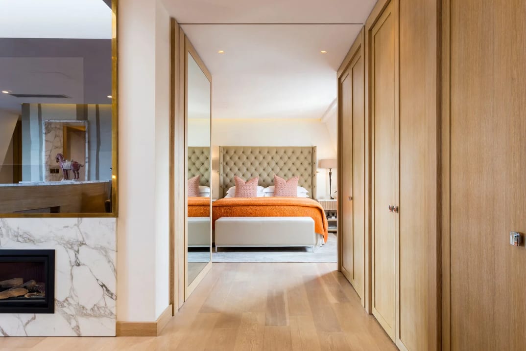 A stylish, contemporary hotel suite with marble fireplace, separate bedroom with plush bedding and light wood accents