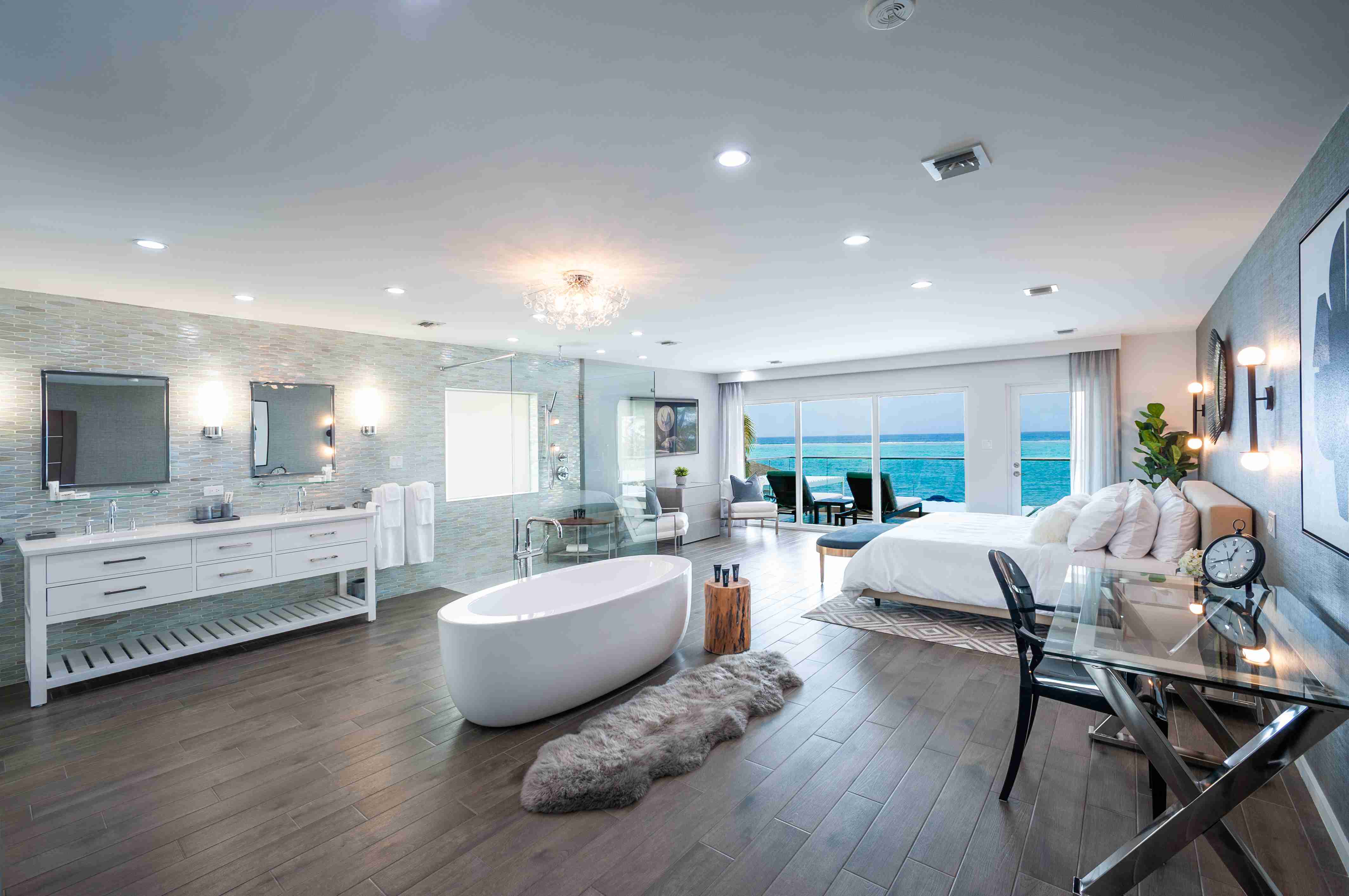 A large open-plan suite with a standalone bathtub in the middle and turquoise ocean views