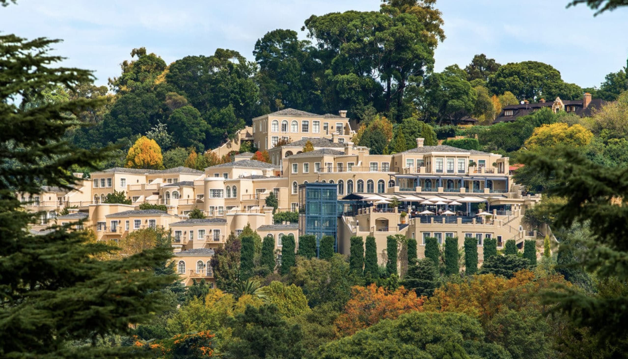 A hillside tan color resort among green trees during day