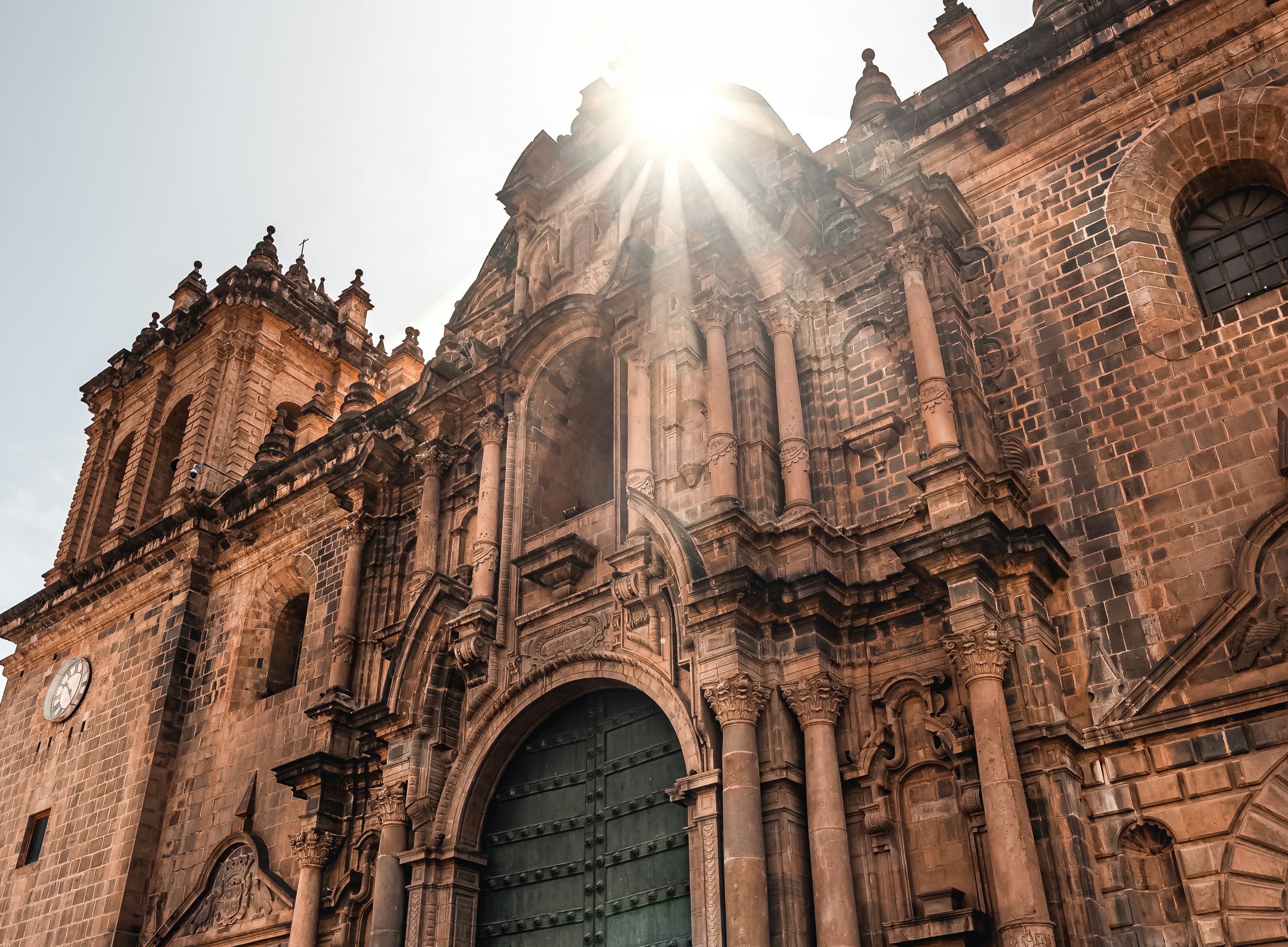a large stone building with the sun shining above it