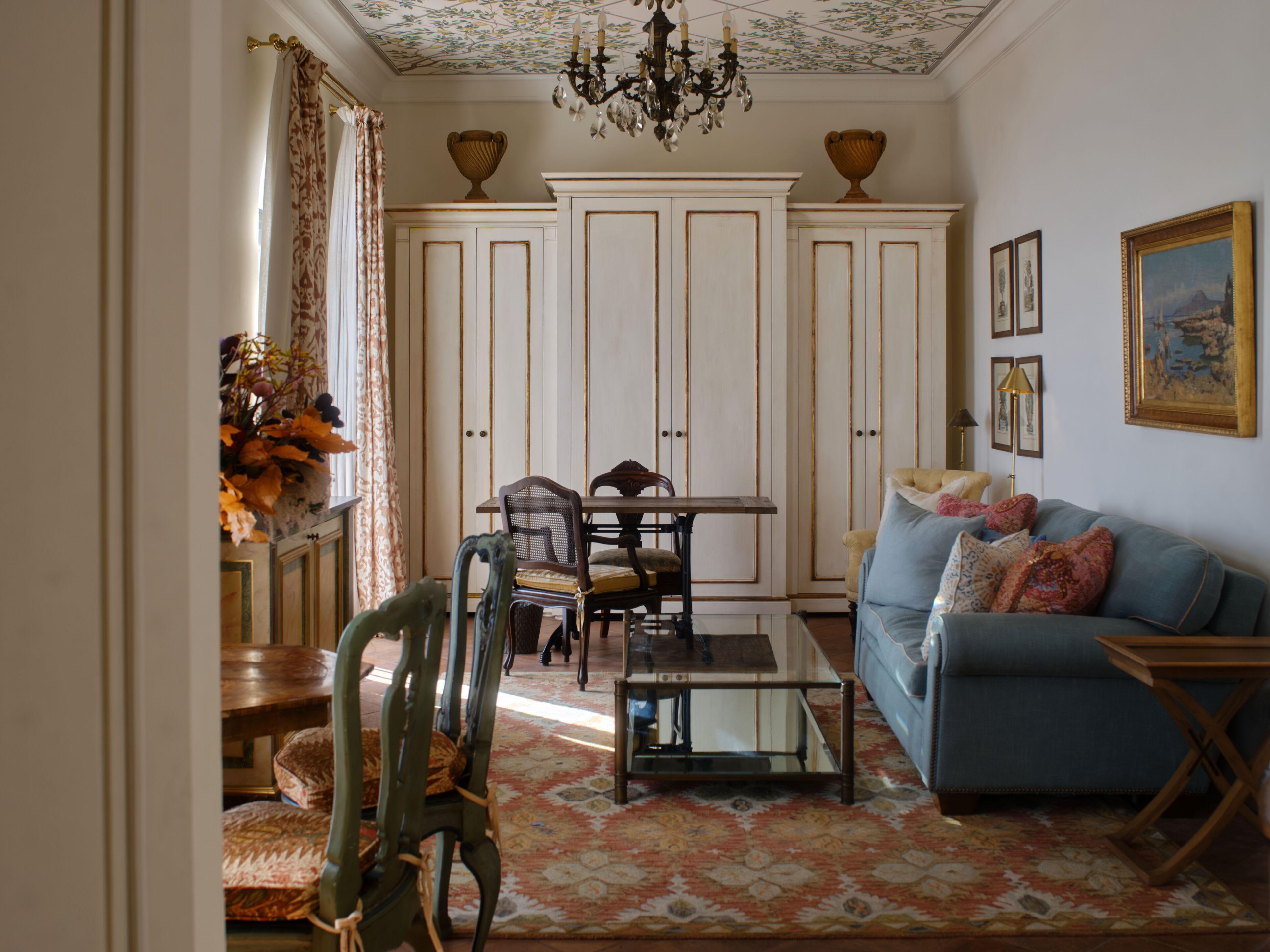 a luxe living room in Italy with a blue couch and a crystal chandelier
