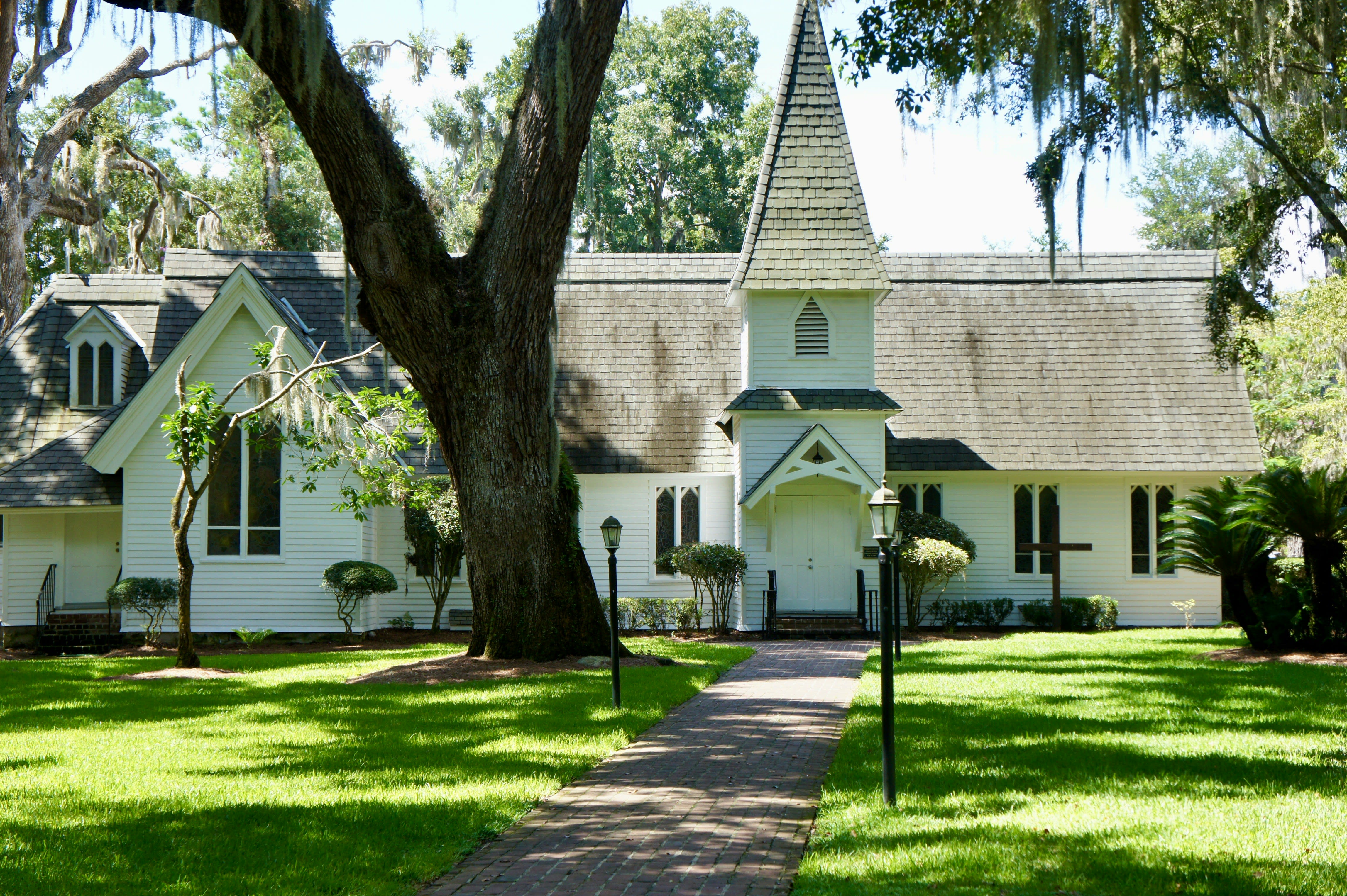 A white building with a spire in front of a manicured lawn