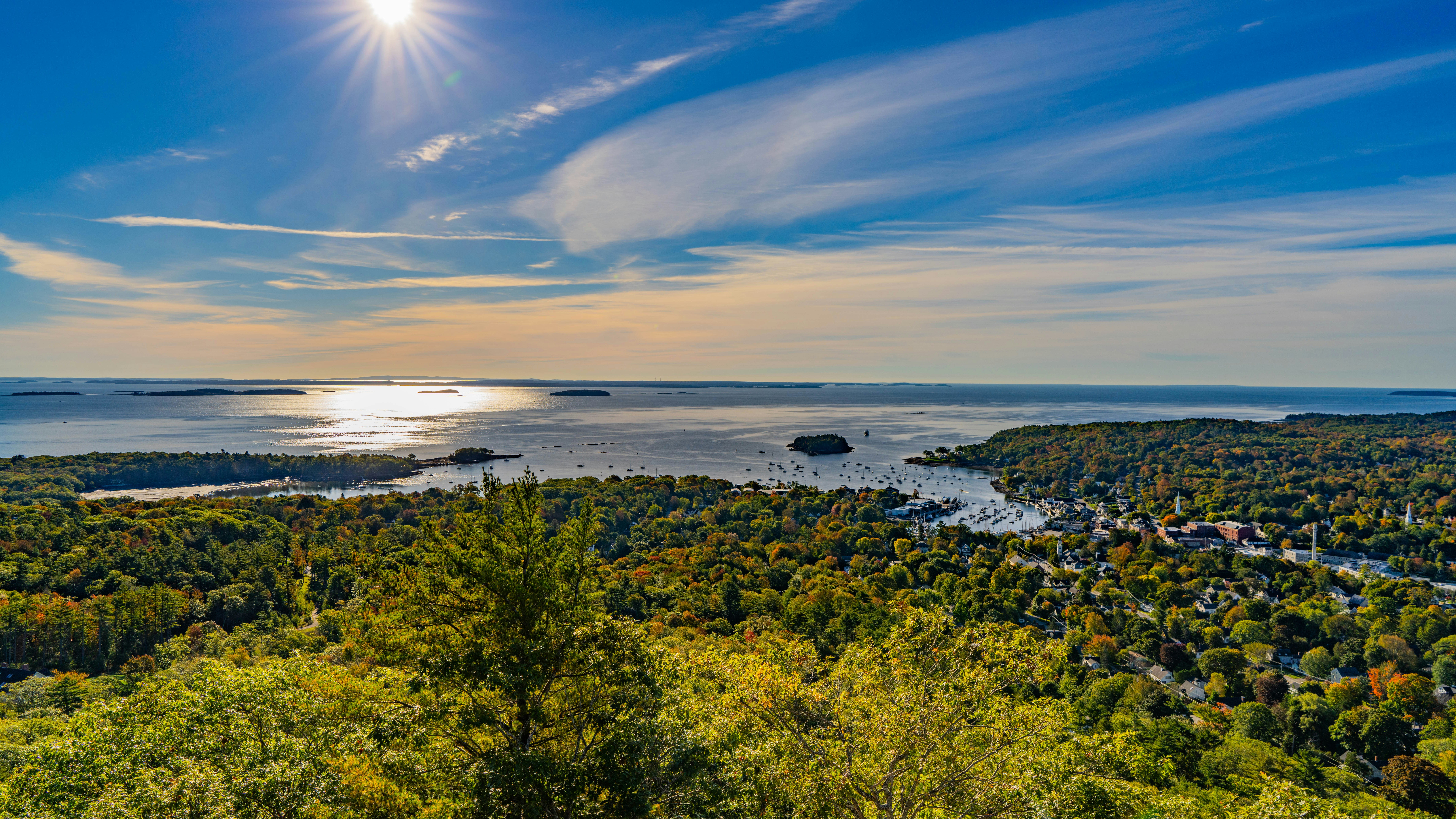 An expansive green space overlooking a rocky shoreline and ocean with the sun low in the sky