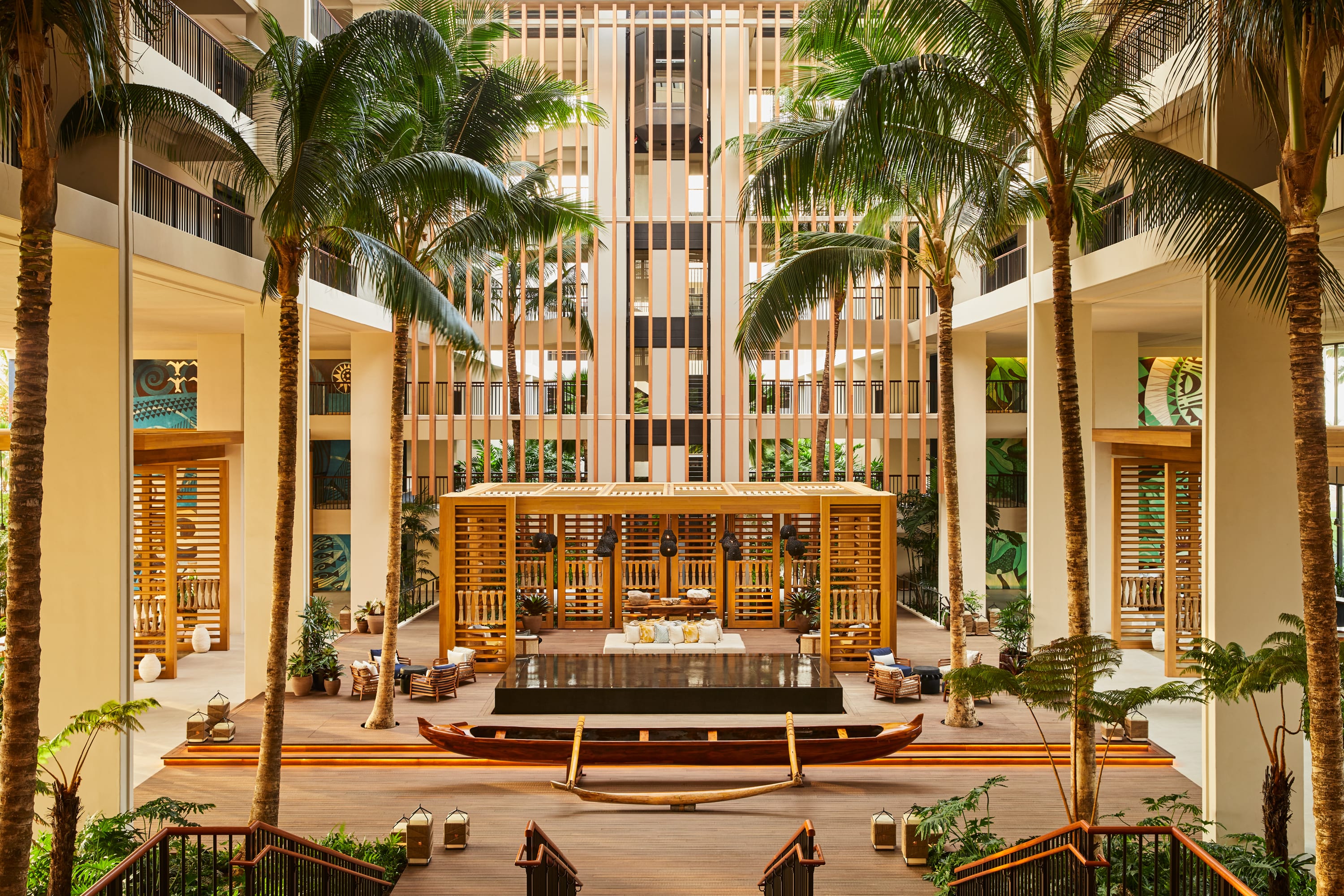 An indoor-outdoor hotel lobby with nautical-inspired decor like canoes and palm trees