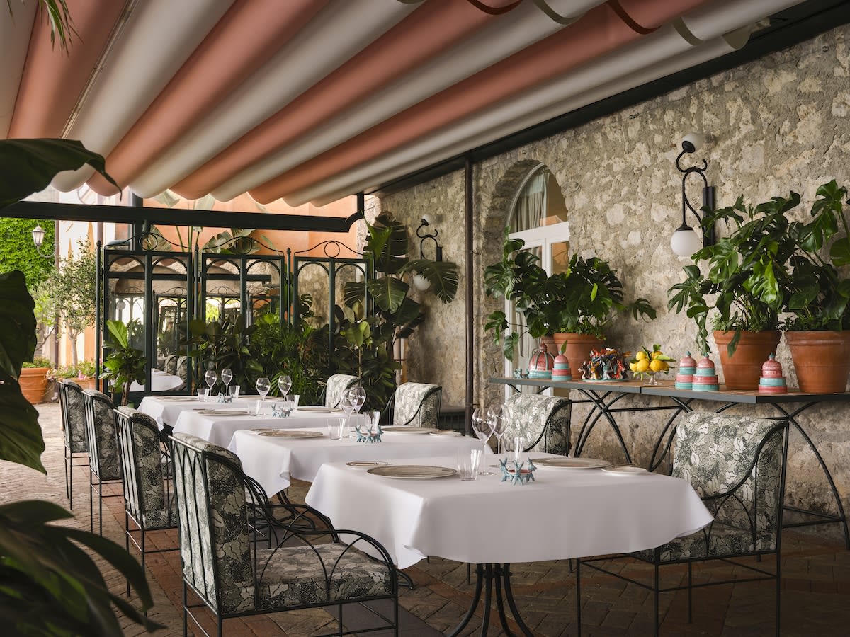 a restaurant terrace with stone walls and elegant white tablecloth-lade tables