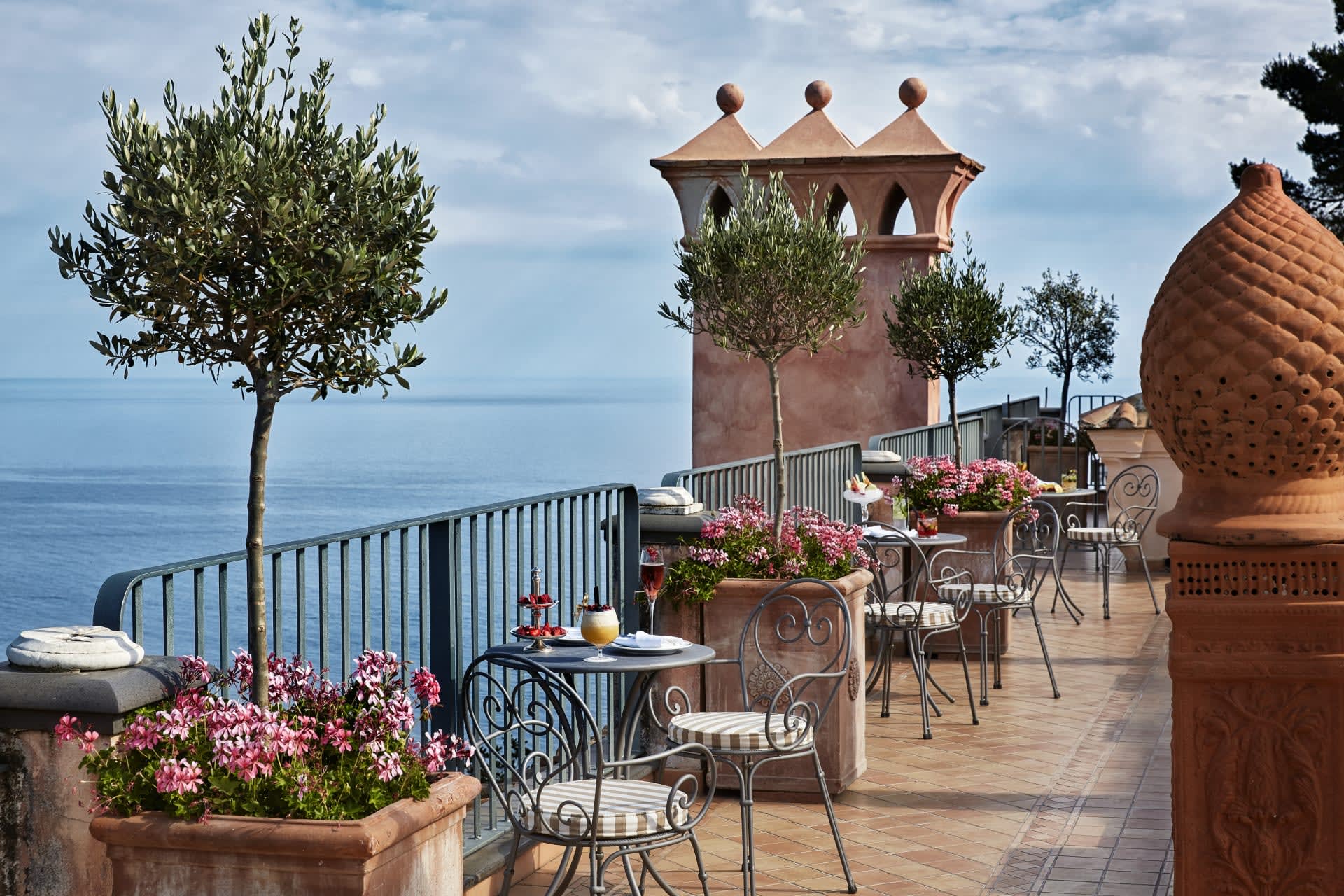 An outdoor terrace with wrought iron table and chairs overlooking the sea