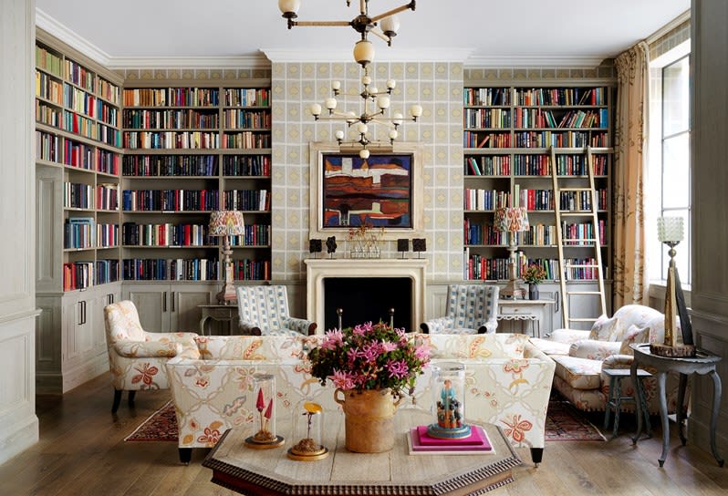 A beautiful hotel library and lounge area with floor-to-ceiling bookshelves, white furnishings, and other bright and colorful decor.