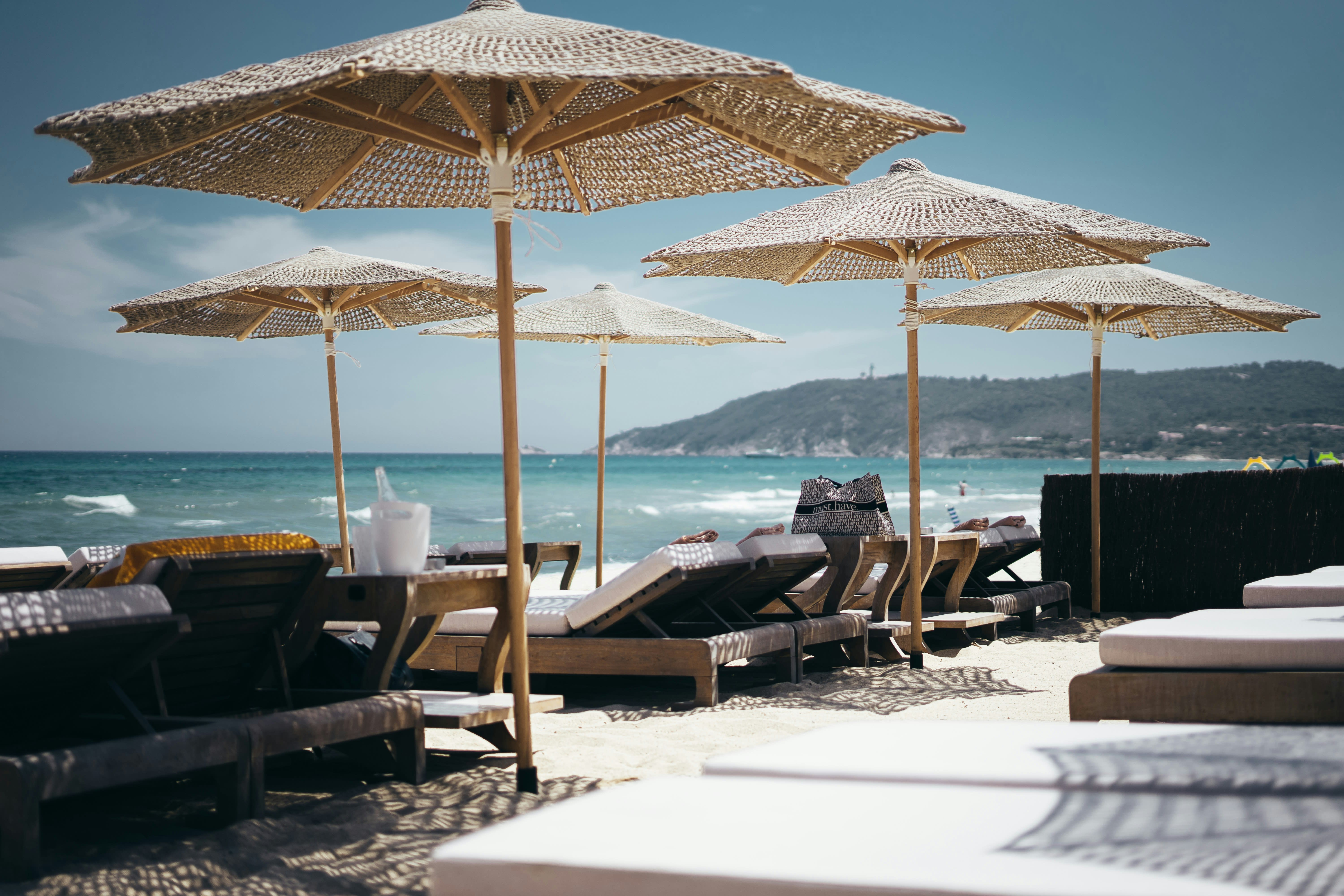Elegant sun loungers with woven parasols on a beautiful beach on a sunny day
