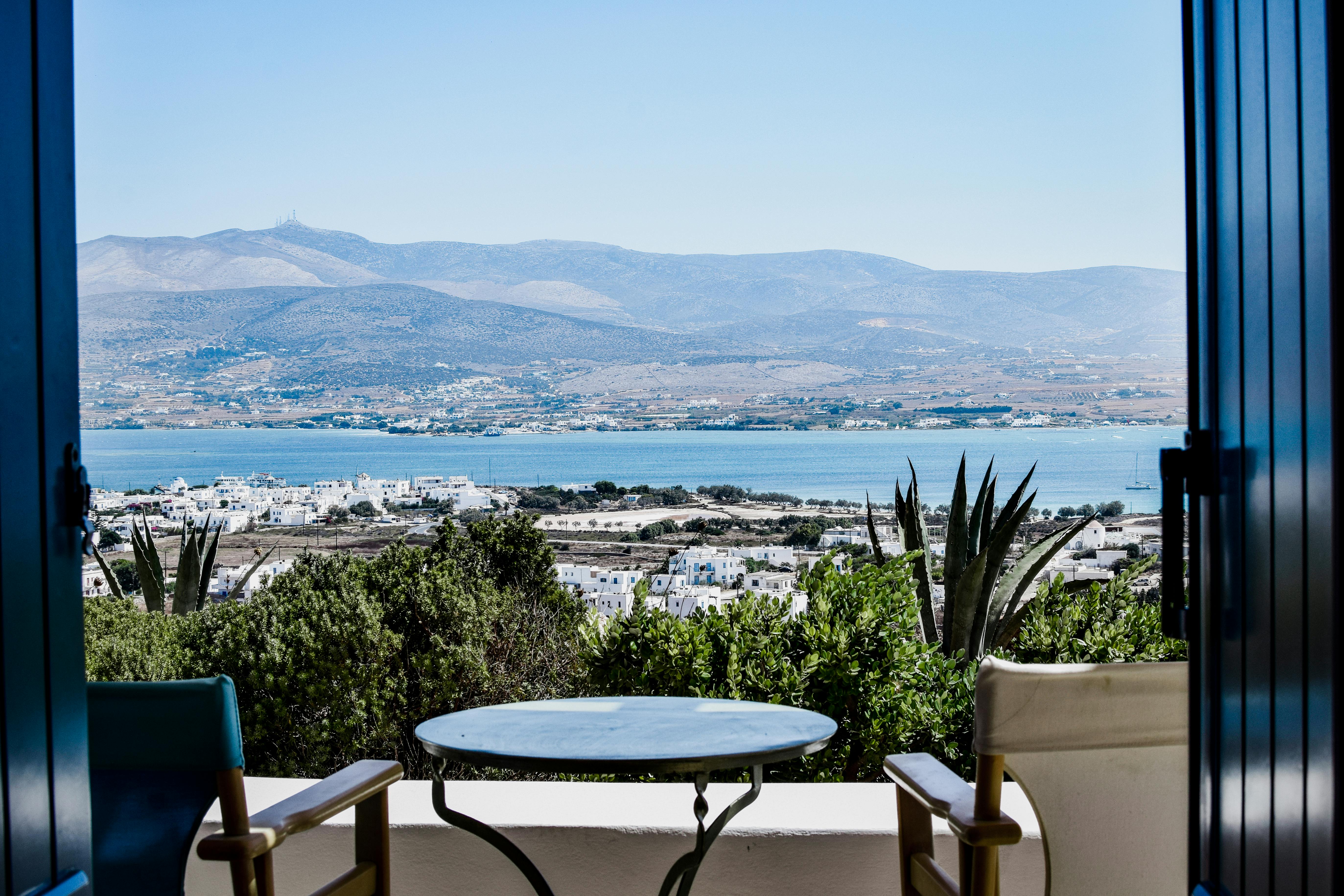 Table and Chairs on Balcony with Sea Coast and Hills behind