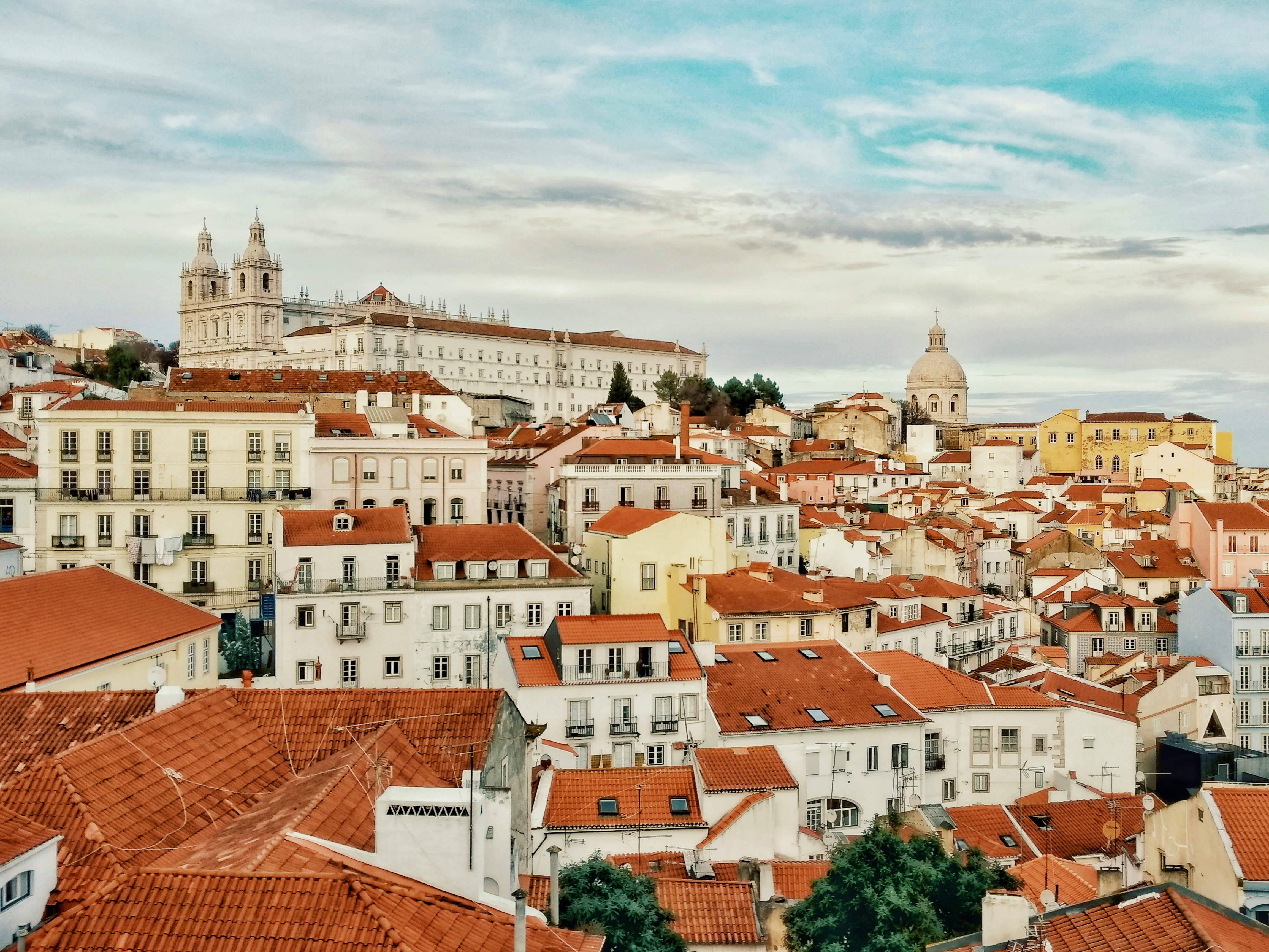hilly city landscape of white buildings and red roofs during daytime