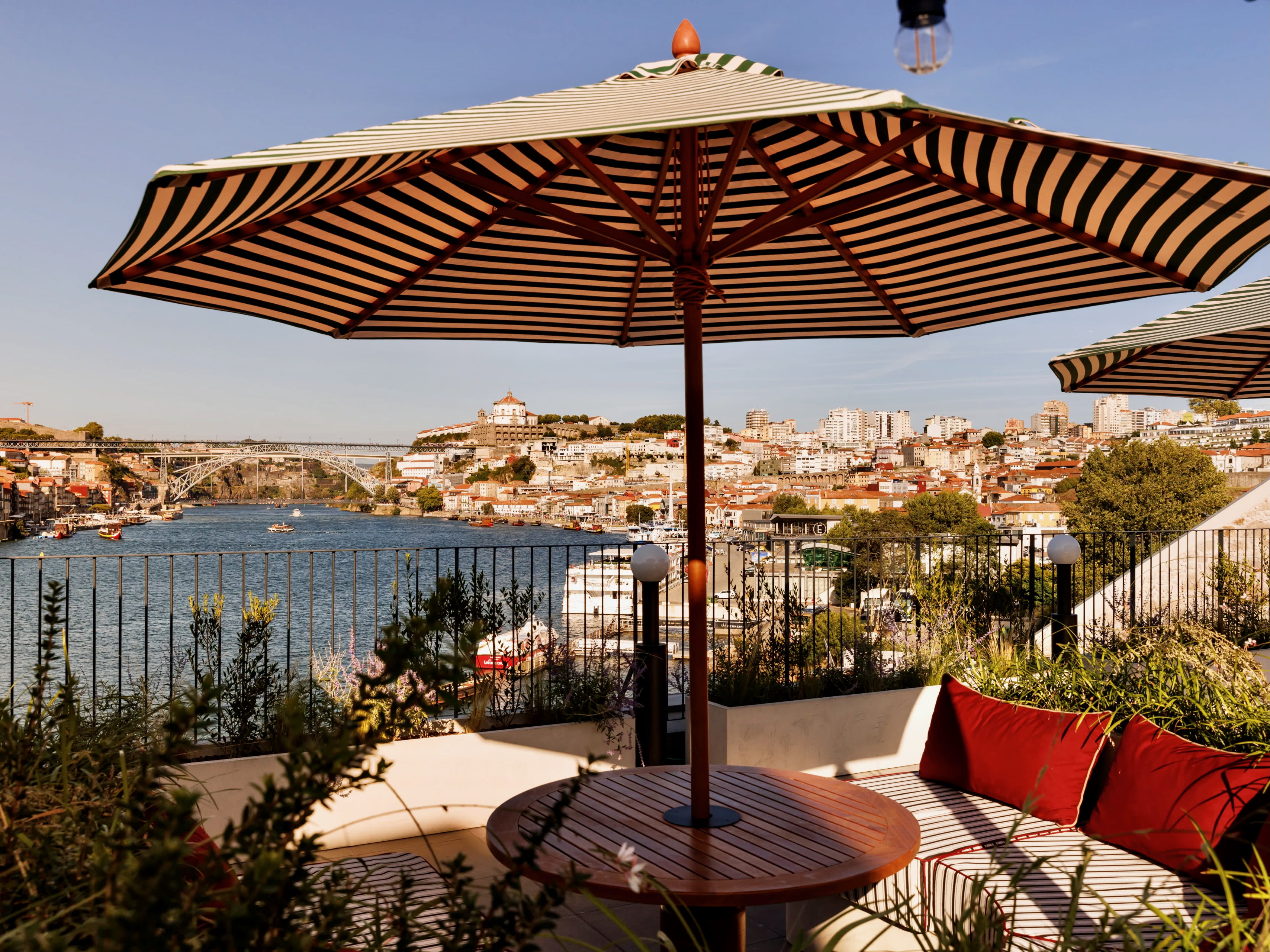 umbrella covered patio with chairs overlooking a river and hilly city during day