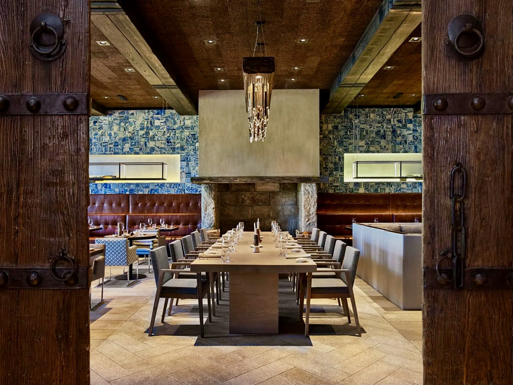 open wood doors to a large dining table in a restaurant with wood ceiling and chandelier
