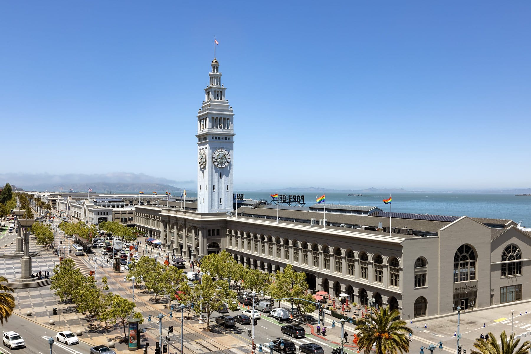 a long seaside building with clock tower lining a busy pedestrian filled street