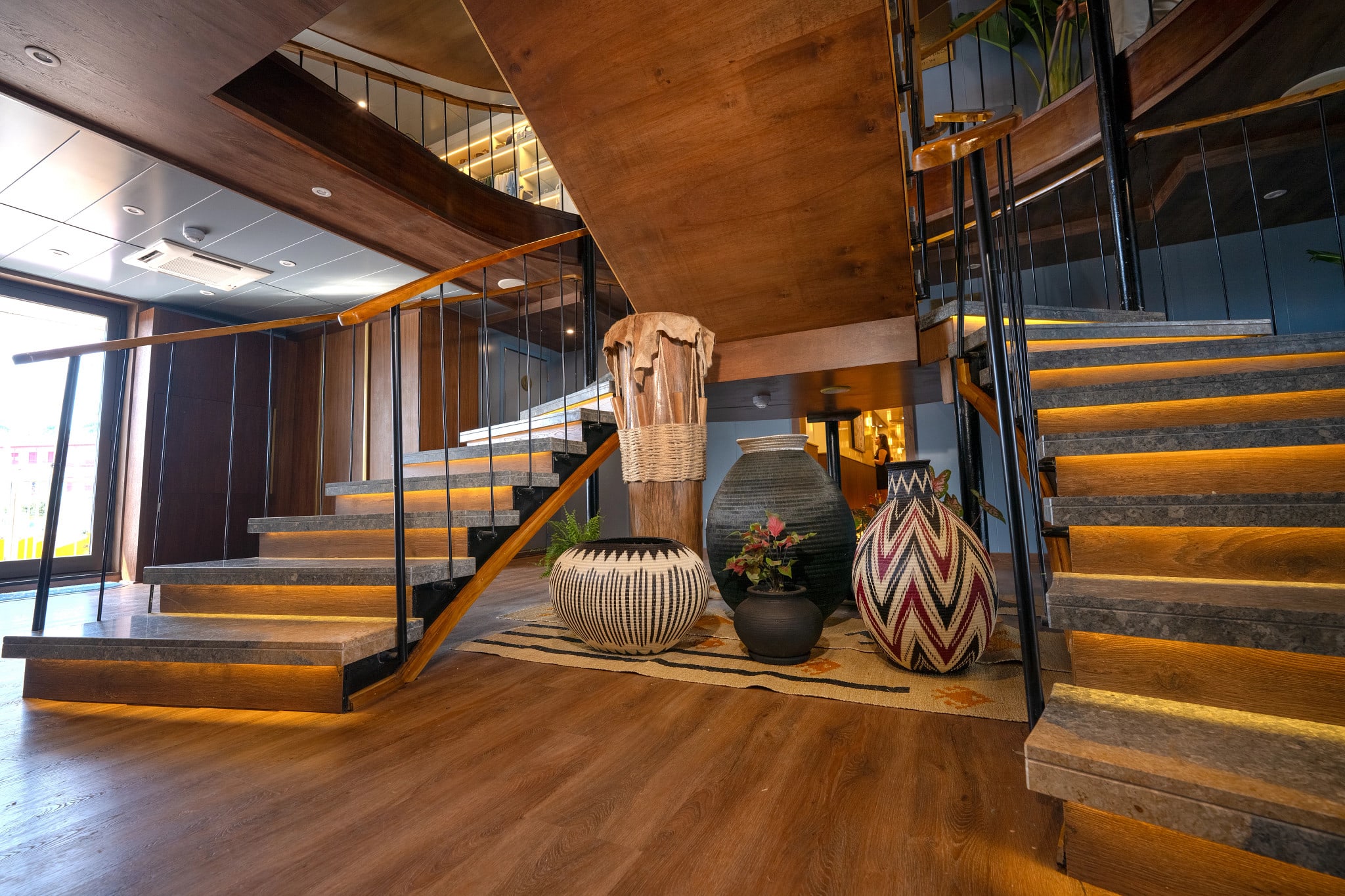 entryway on a cruise ship with two wooden staircases and decorative art
