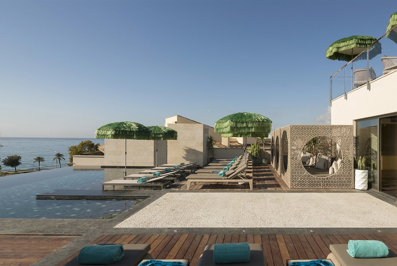 A beautiful rooftop with infinity pool, wooden decking, and sun loungers against a blue sky