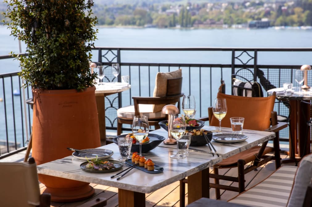 An elegant table with dining setup overlooking a lake and greenery
