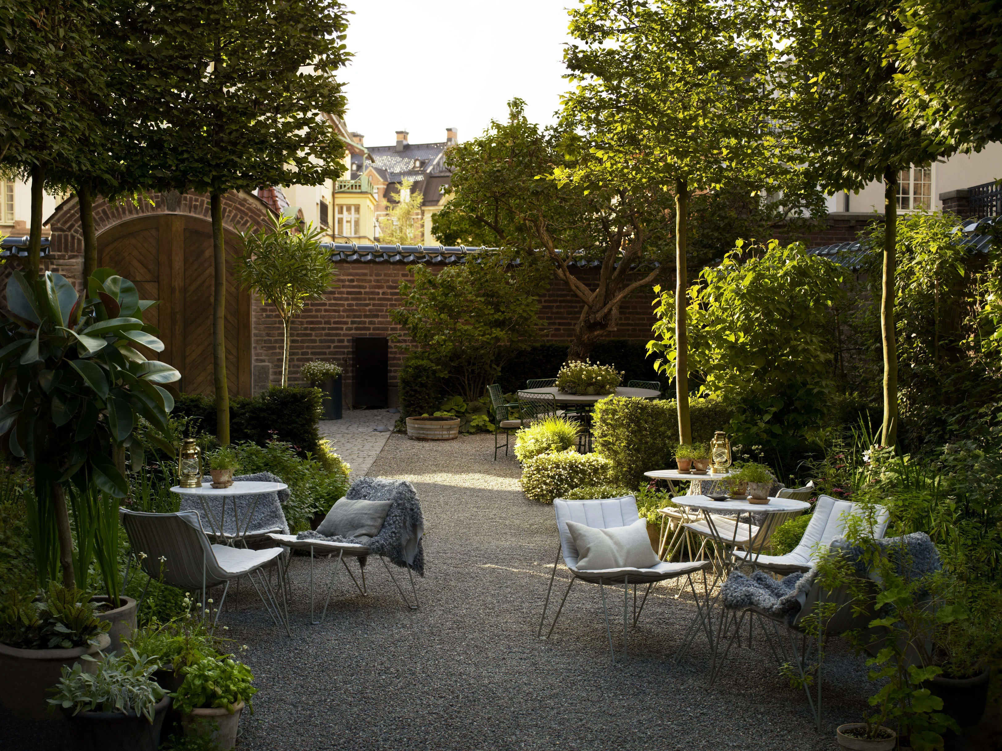 table and chairs on gravel surrounded by a walled in garden courtyard during day