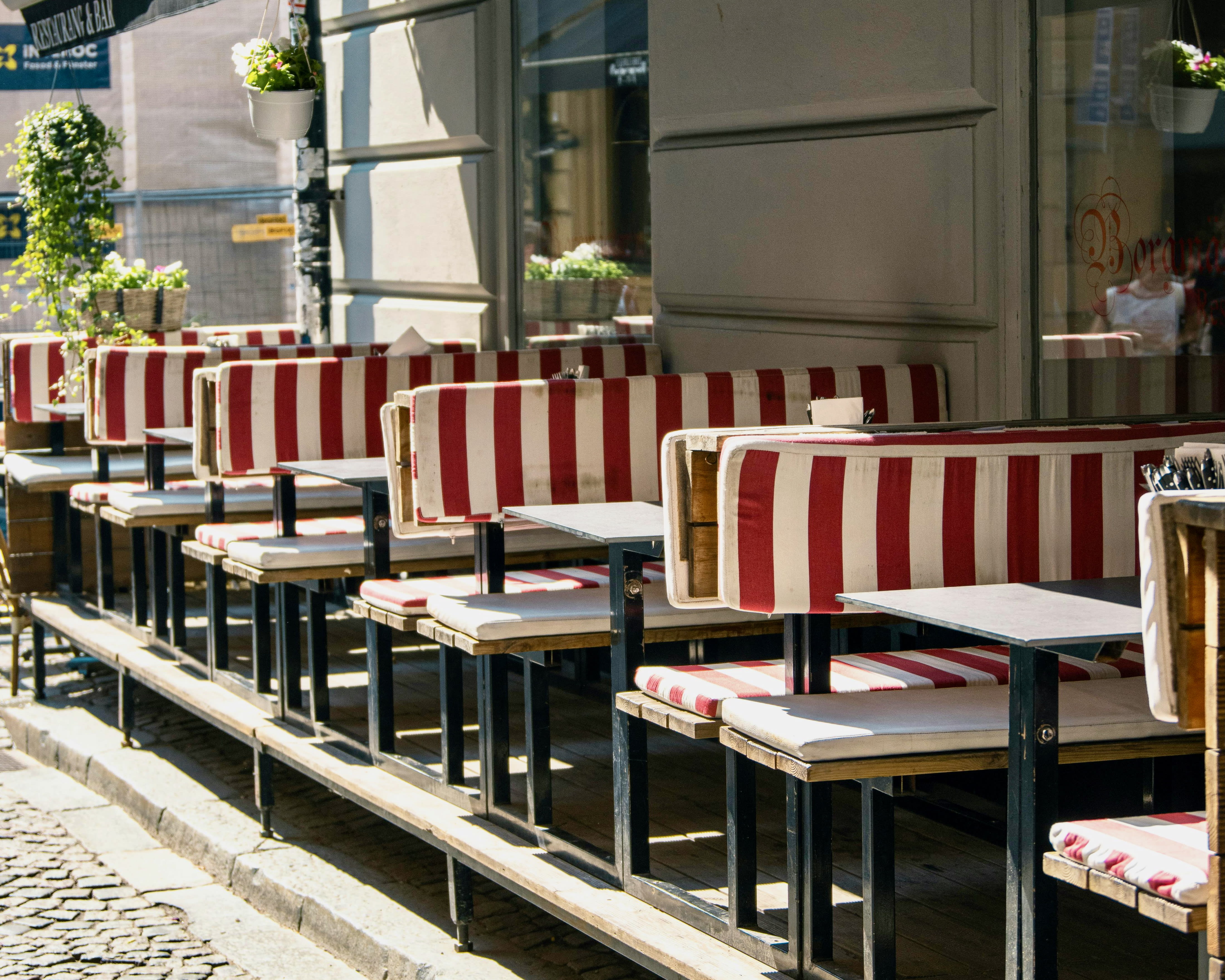 red and white striped outdoor benches with tables lining a restaurant patio during day