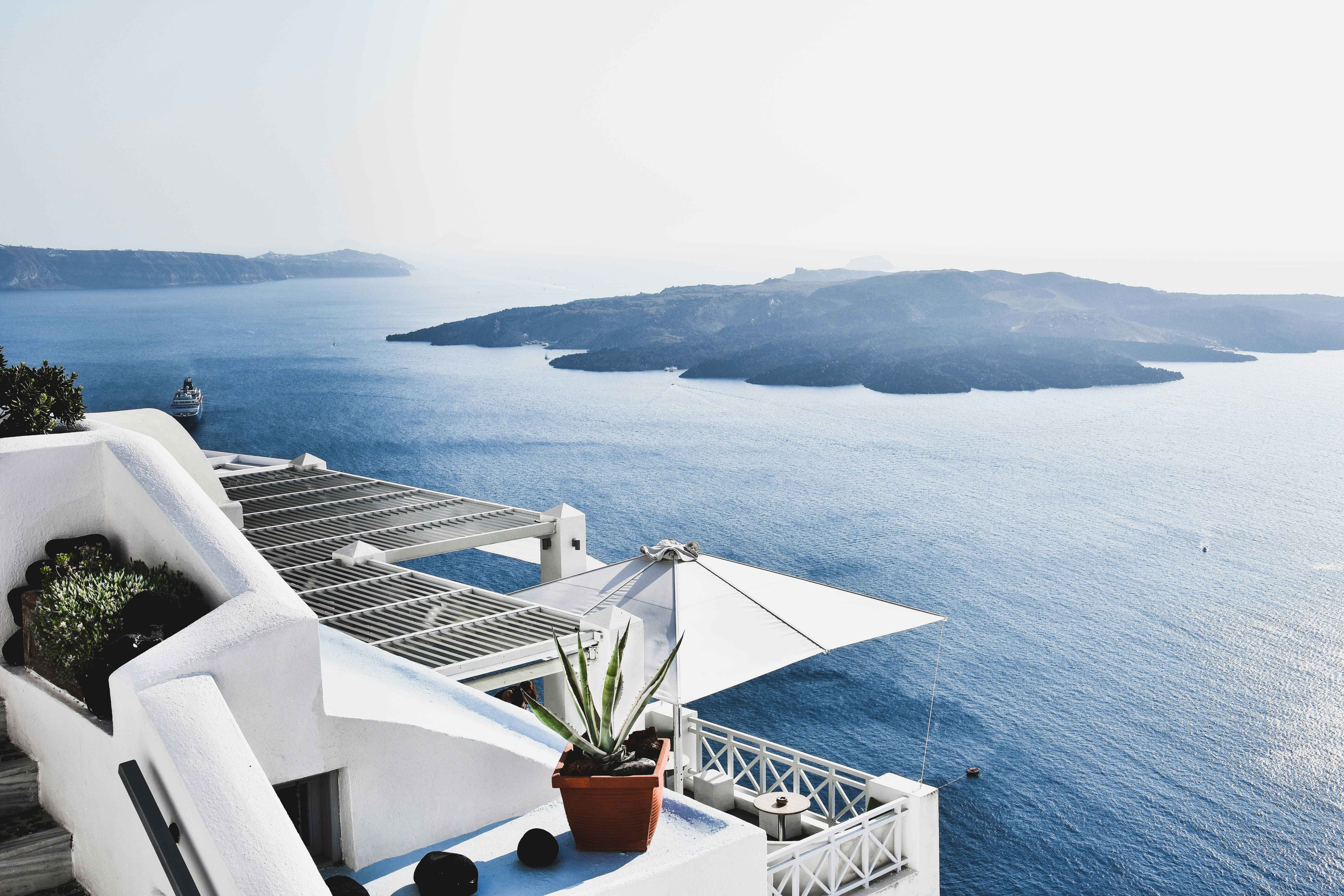 Whitewashed terrace with sea views overlooking a blue caldera and island in Santorini, Greece