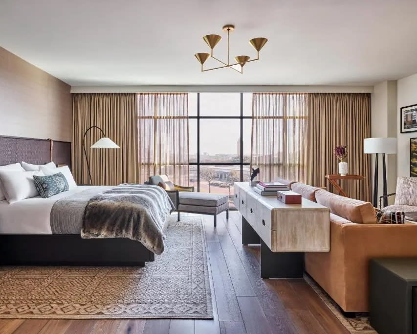 a modern Southern style hotel room with tan leather and wood, faux fur accents, and gold chandelier