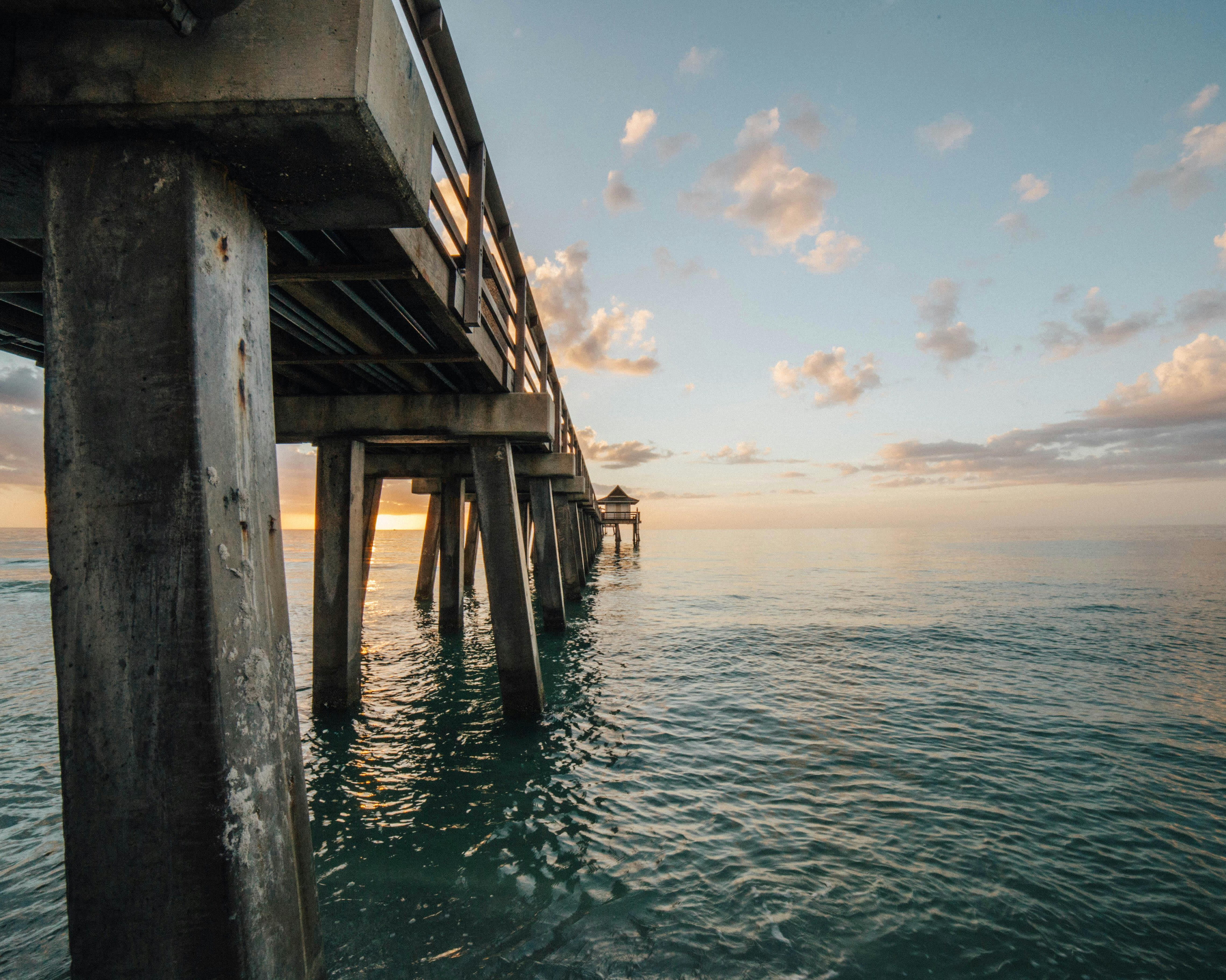 a wood pier over the ocean at sunset