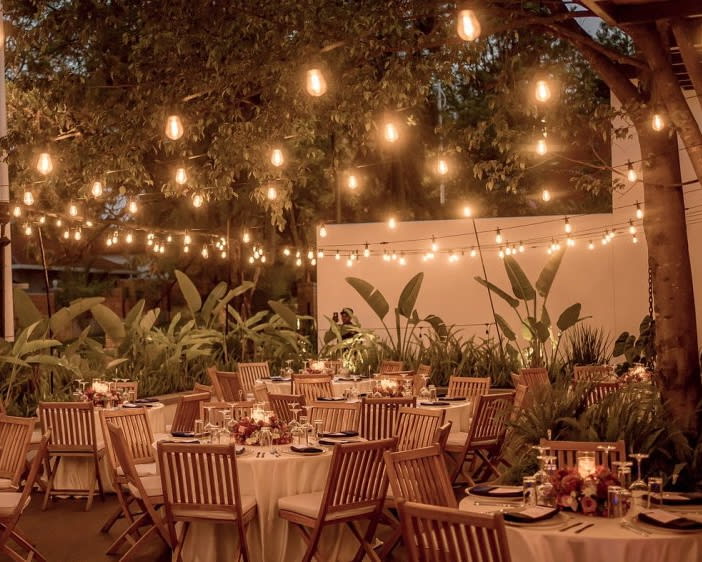 an outdoor restaurant patio at night with lights and greenery