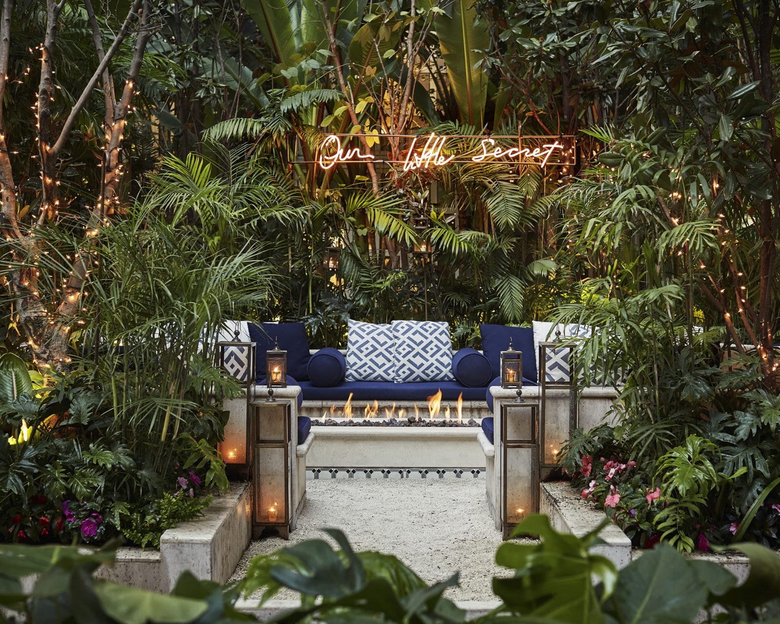 firepit and seating area surrounded by greenery and lights