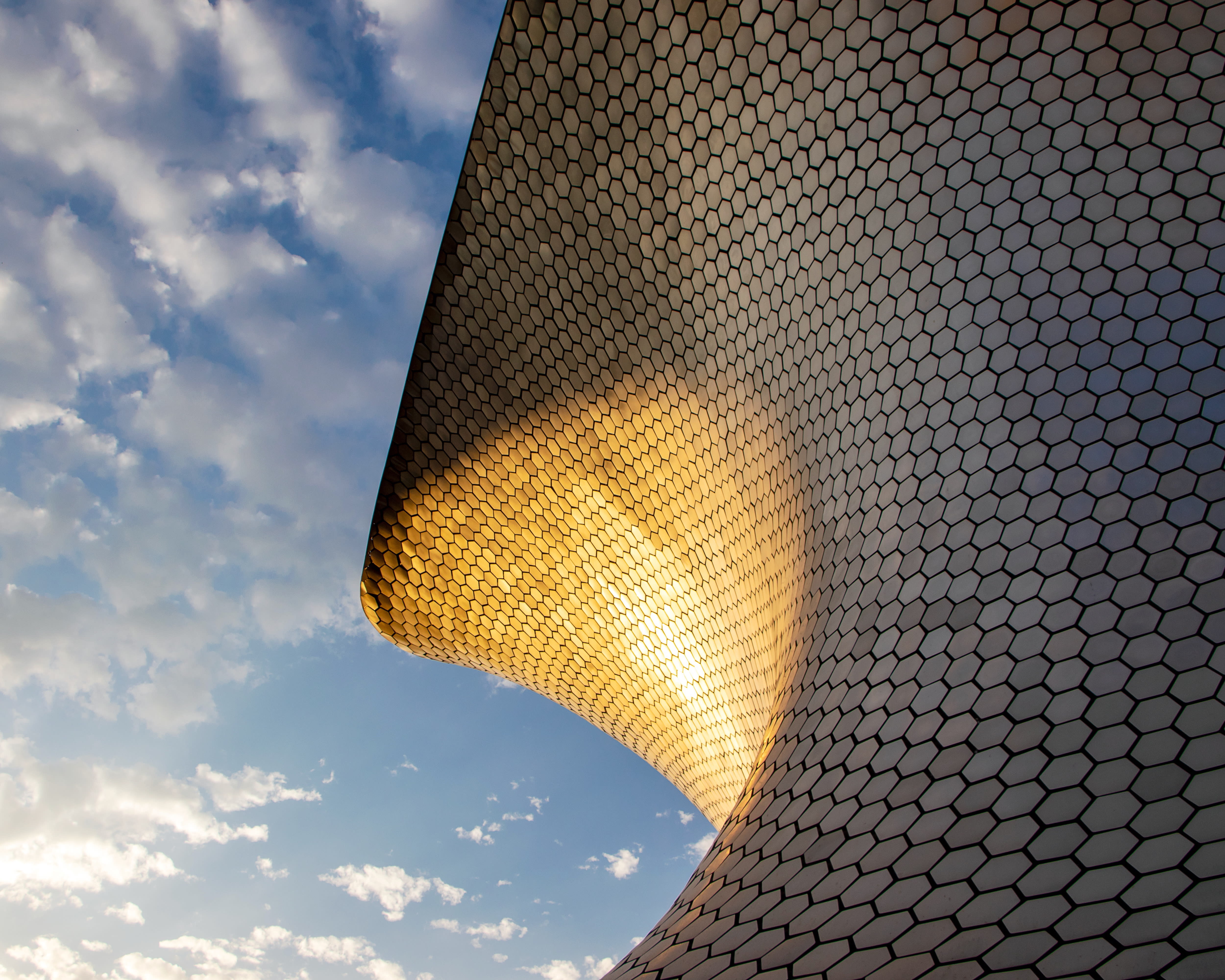 modern metal sloped building with sun reflecting under blue sky