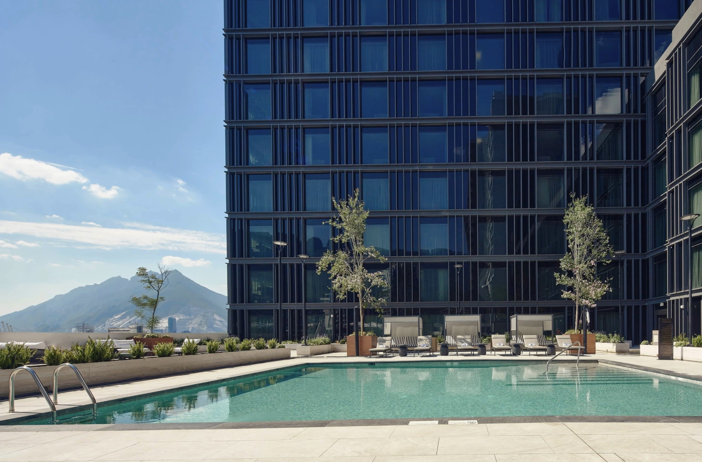 outdoor pool with a tall building and a mountain in the background