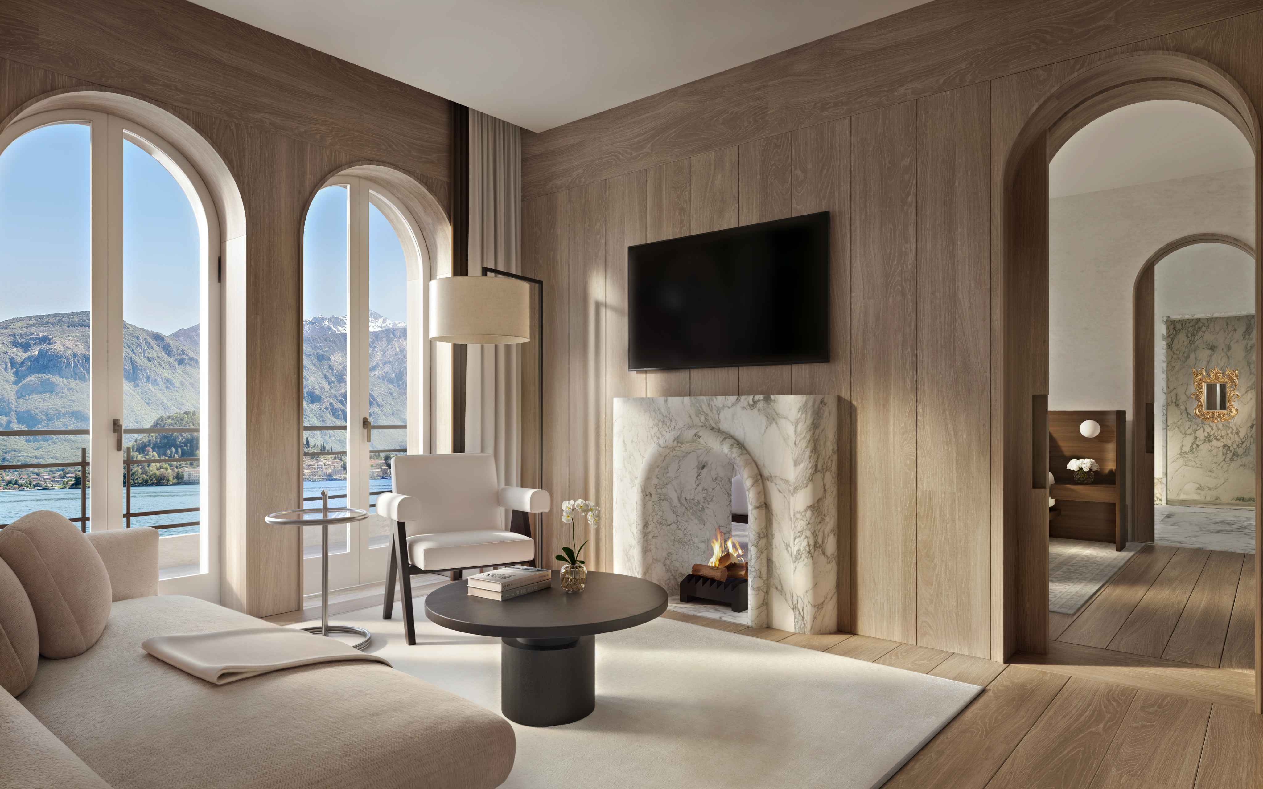 Elegant penthouse living room with arched windows, a marble fireplace, and views of Lake Como and surrounding mountains.