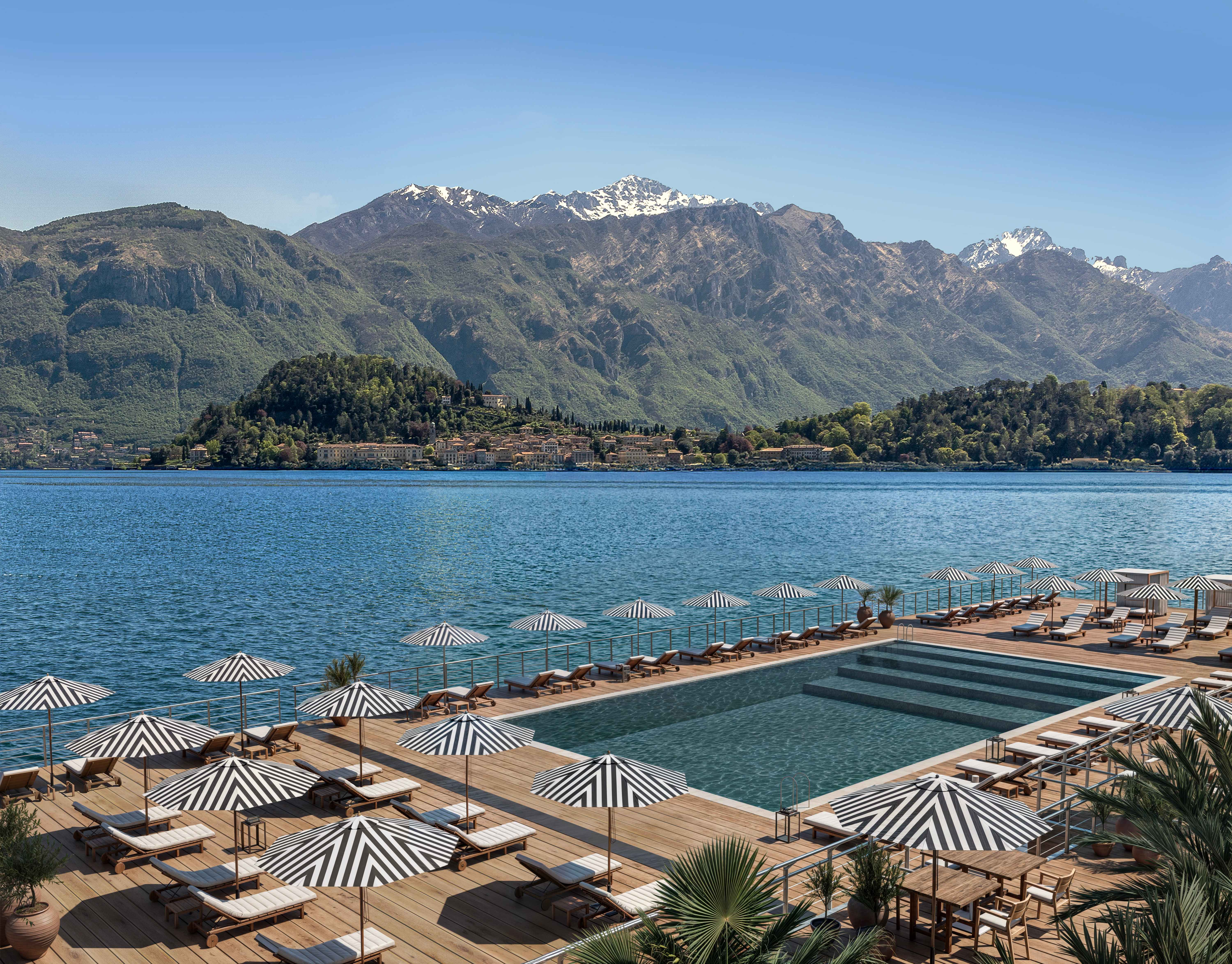 Lakeside infinity pool with striped umbrellas and sun loungers overlooking Lake Como and the surrounding mountains.