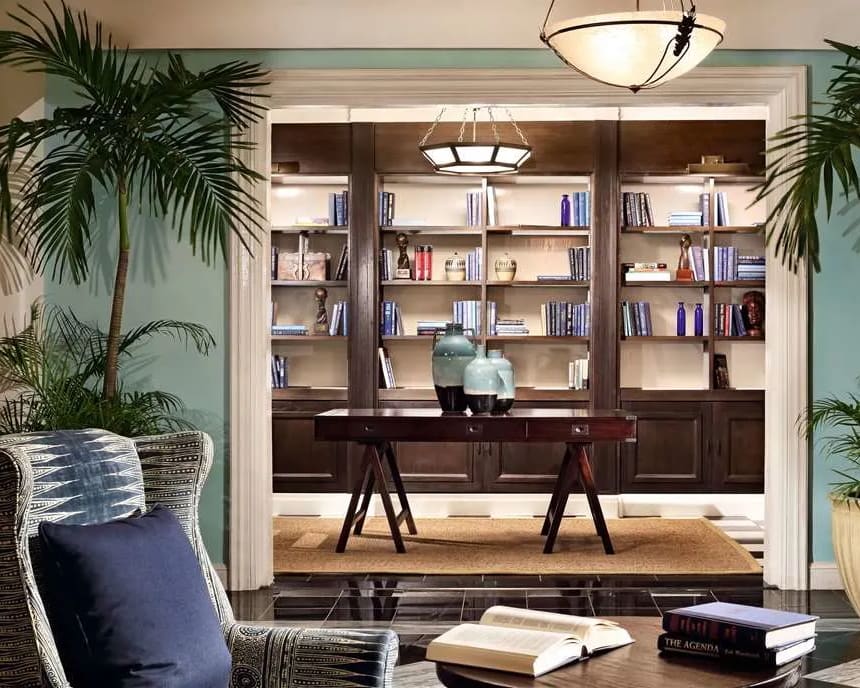 A library setting with chair and books and dark wood shelves and green walls
