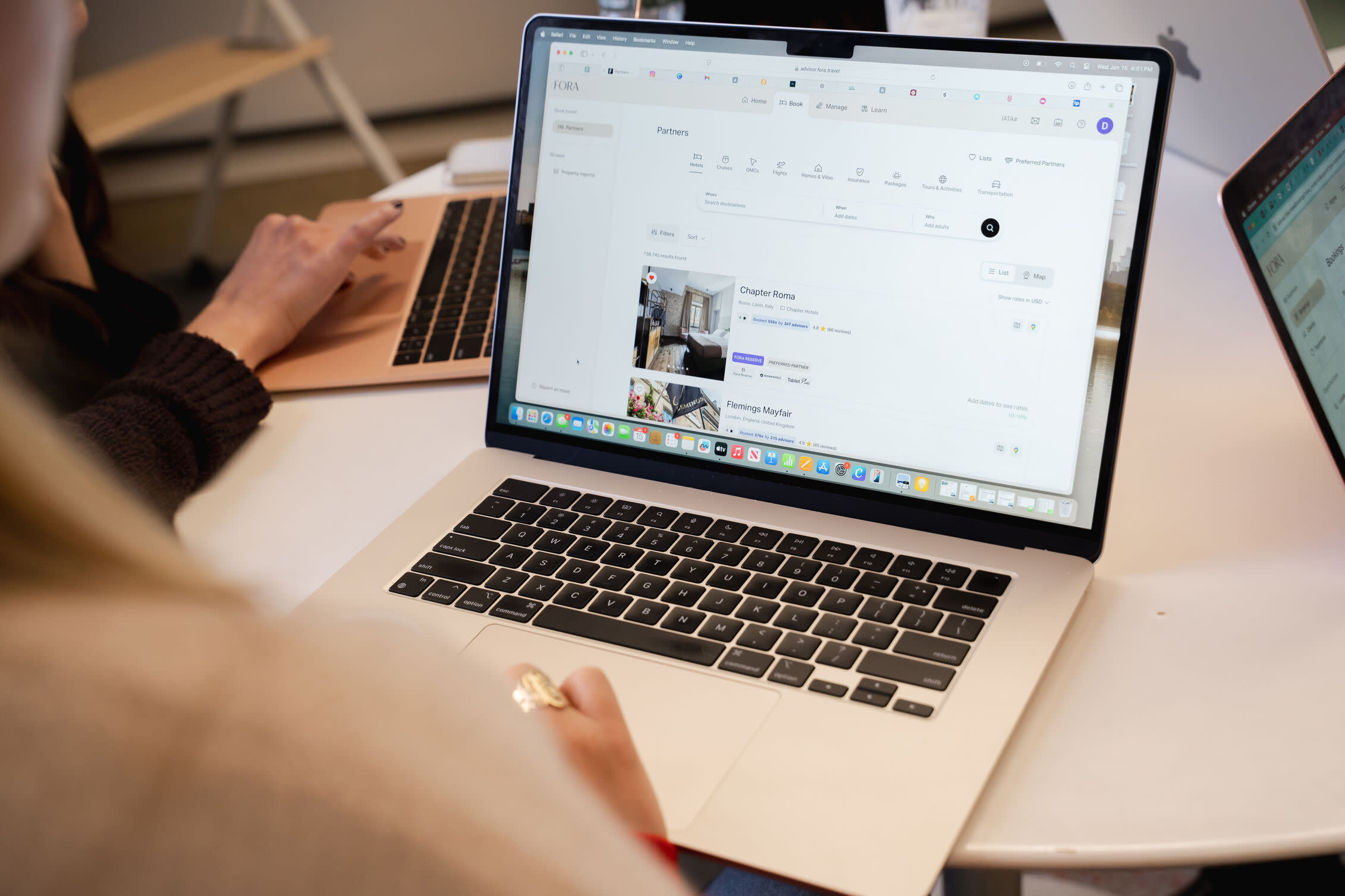 A person using a laptop to view Fora’s booking platform, displaying hotel partner listings on the screen.