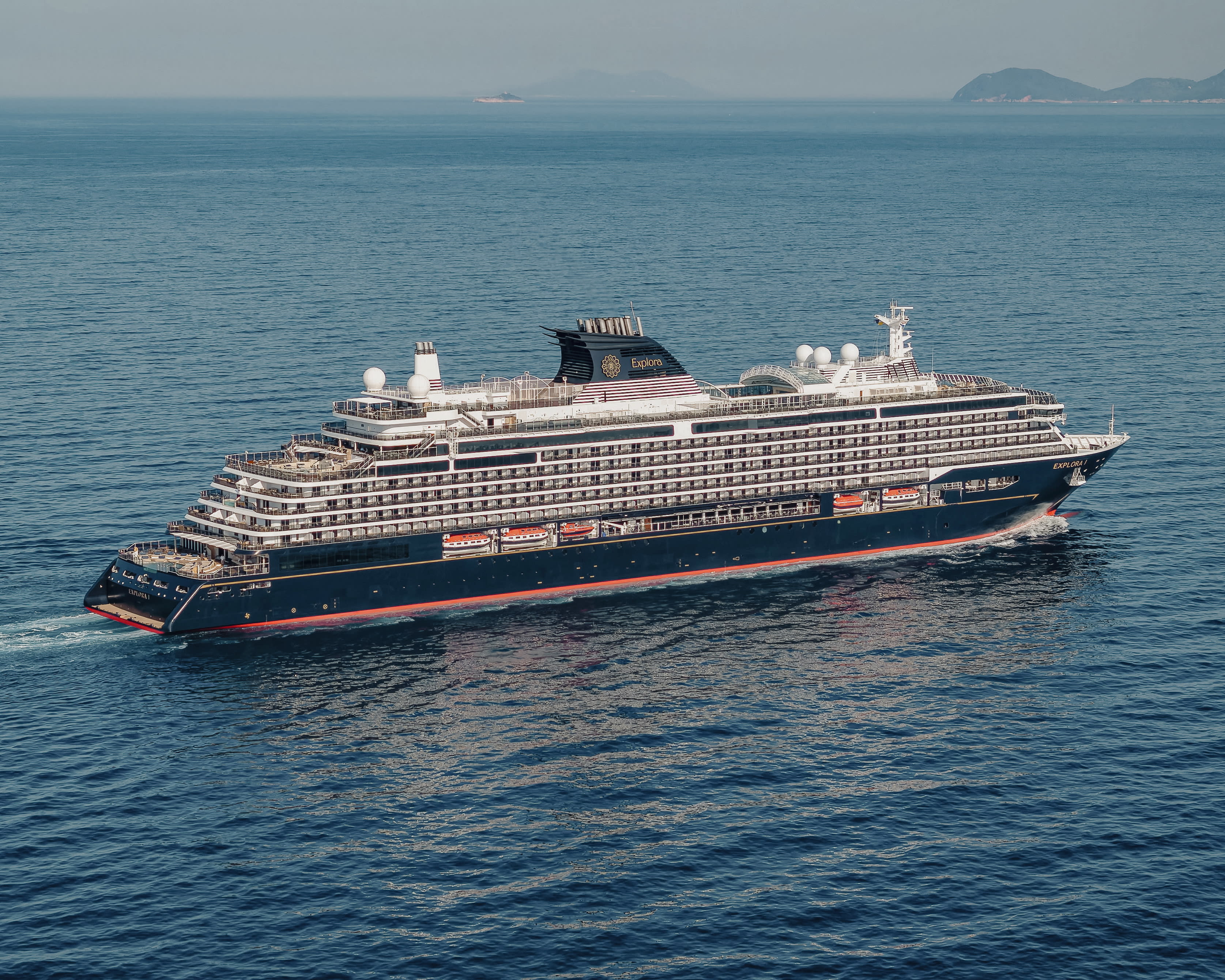 A medium sized modern cruise ship sailing in blue ocean waters during day