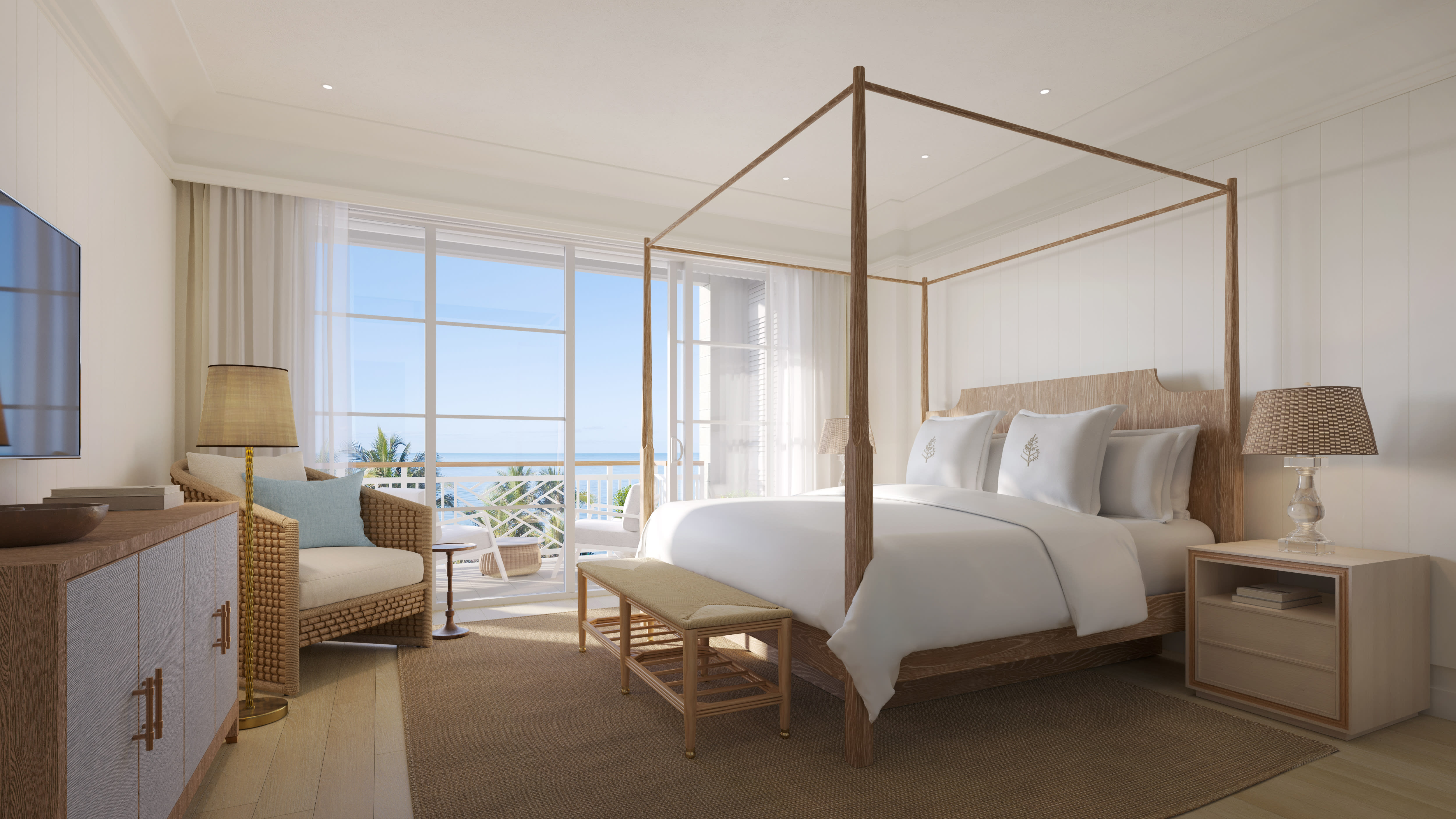 Bright ocean-view suite with a four-poster bed, neutral-toned decor, and a balcony overlooking the sea, featuring coastal-inspired furniture and natural light.