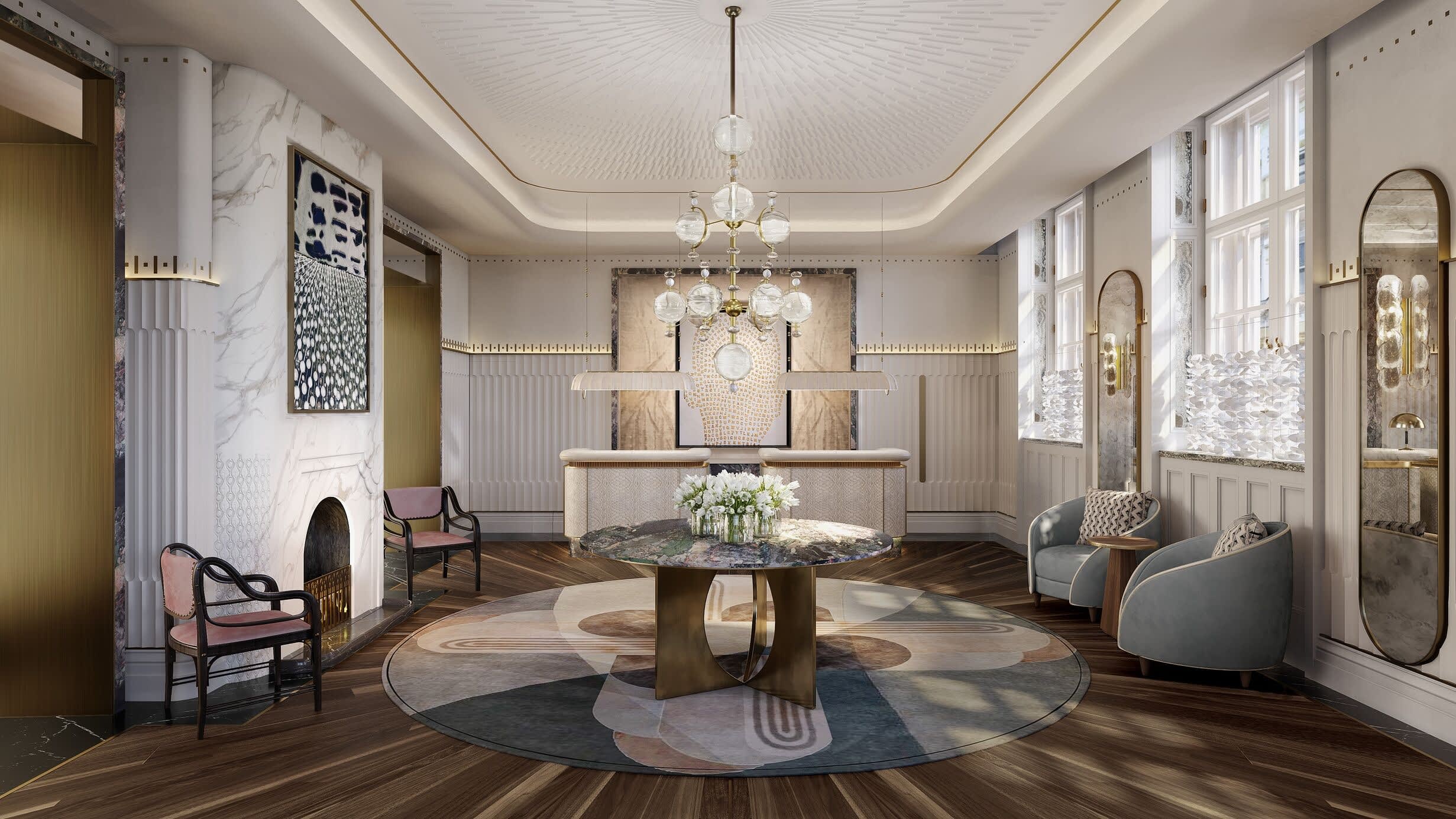 Elegant hotel reception with marble fireplace, gold accents, and Art Deco-inspired design featuring a round center table with fresh flowers and a modern chandelier.